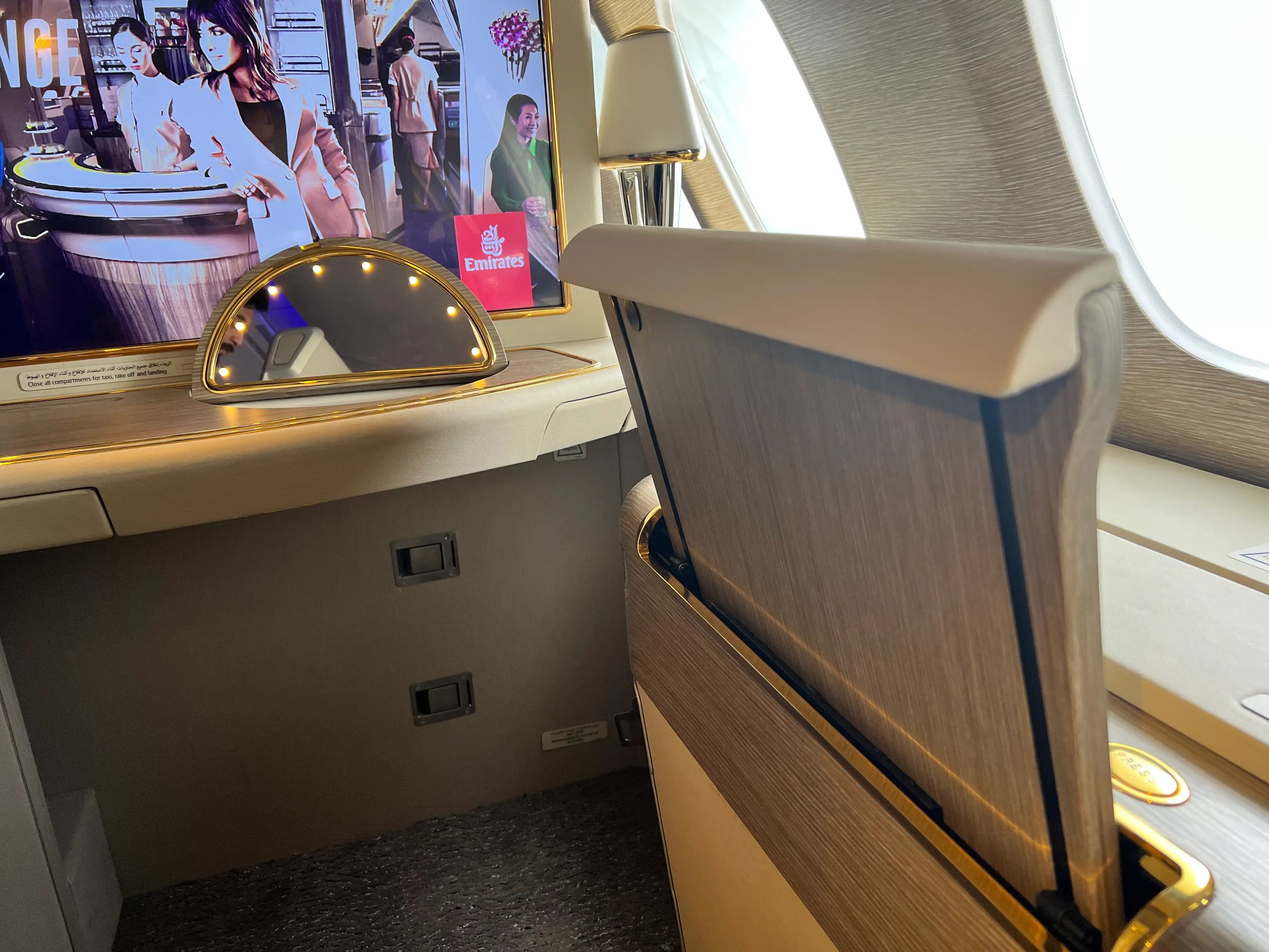 A dining table appears half-stowed away, sticking upwards, in an Emirates A380 first class suite