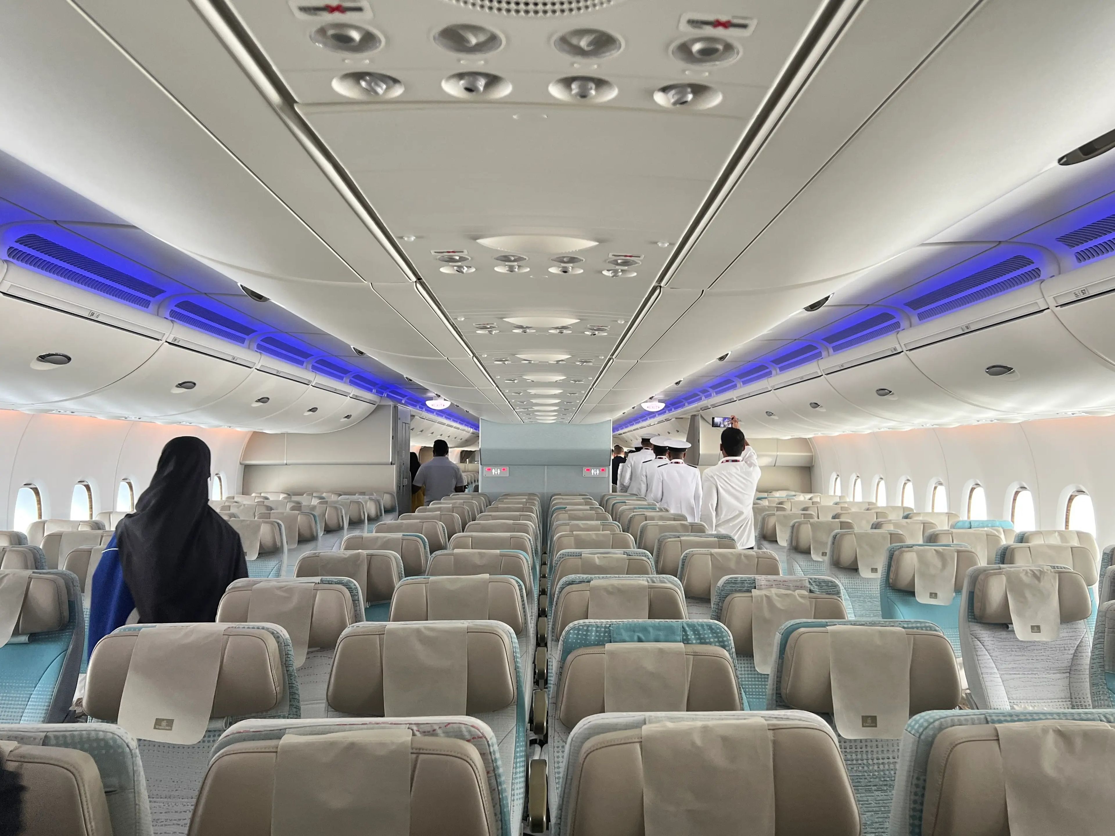 The economy cabin on an Emirates A380 features cyan and grey seats in a 3-4-3 layout.