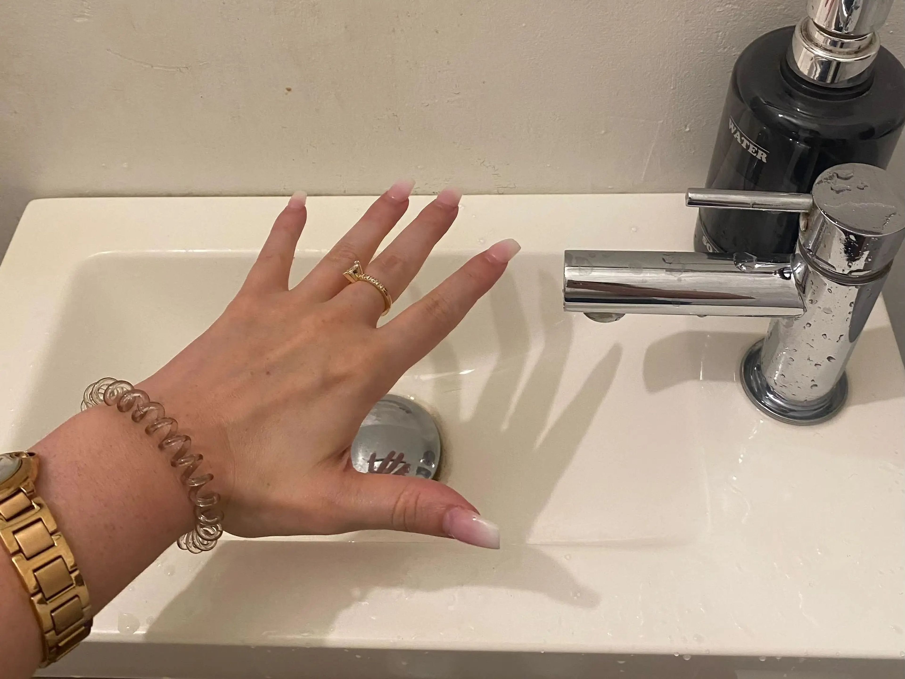 A hand being held over a sink.
