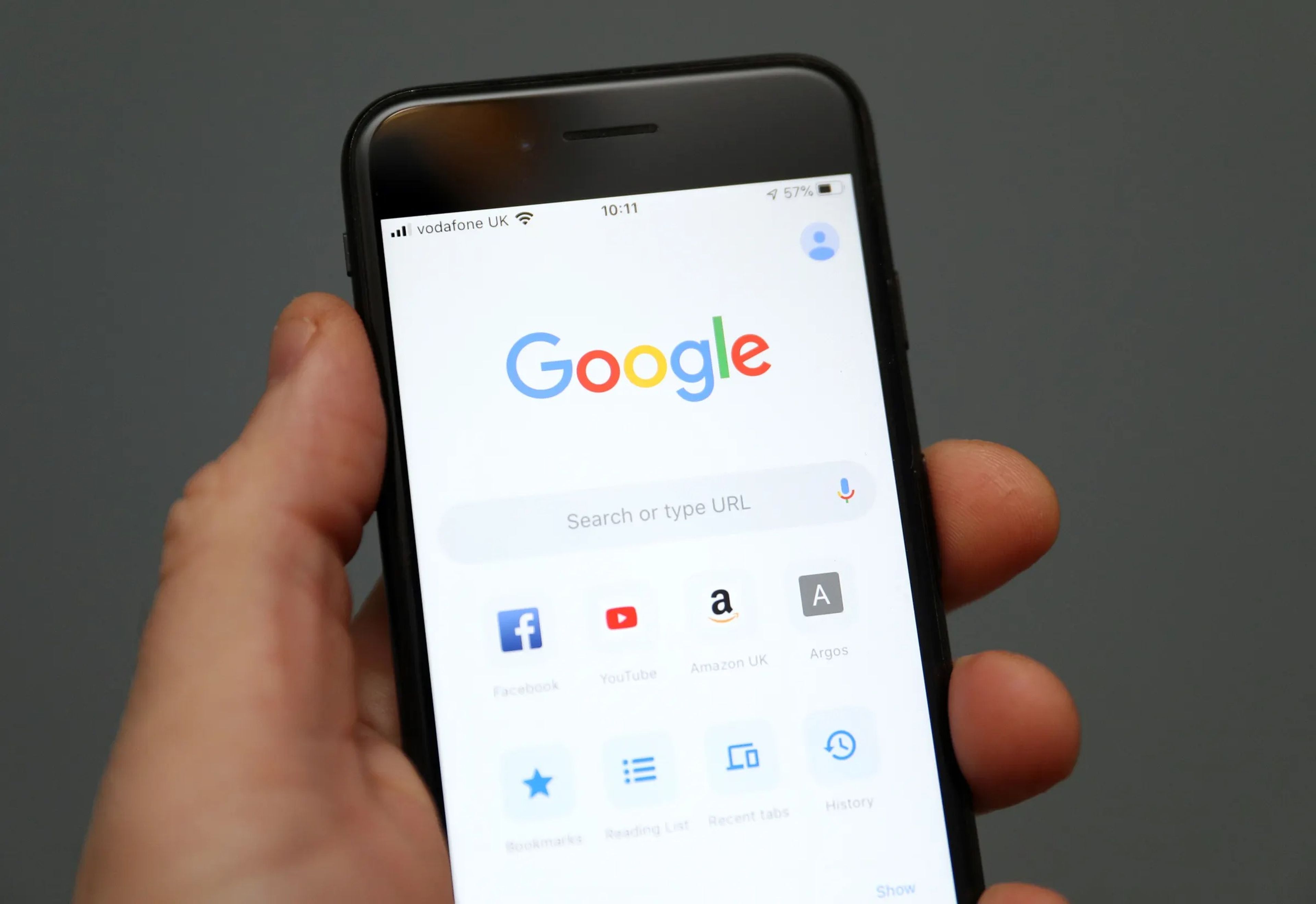Una mano sujetando un iPhone con la pestaña de Google abierta. 