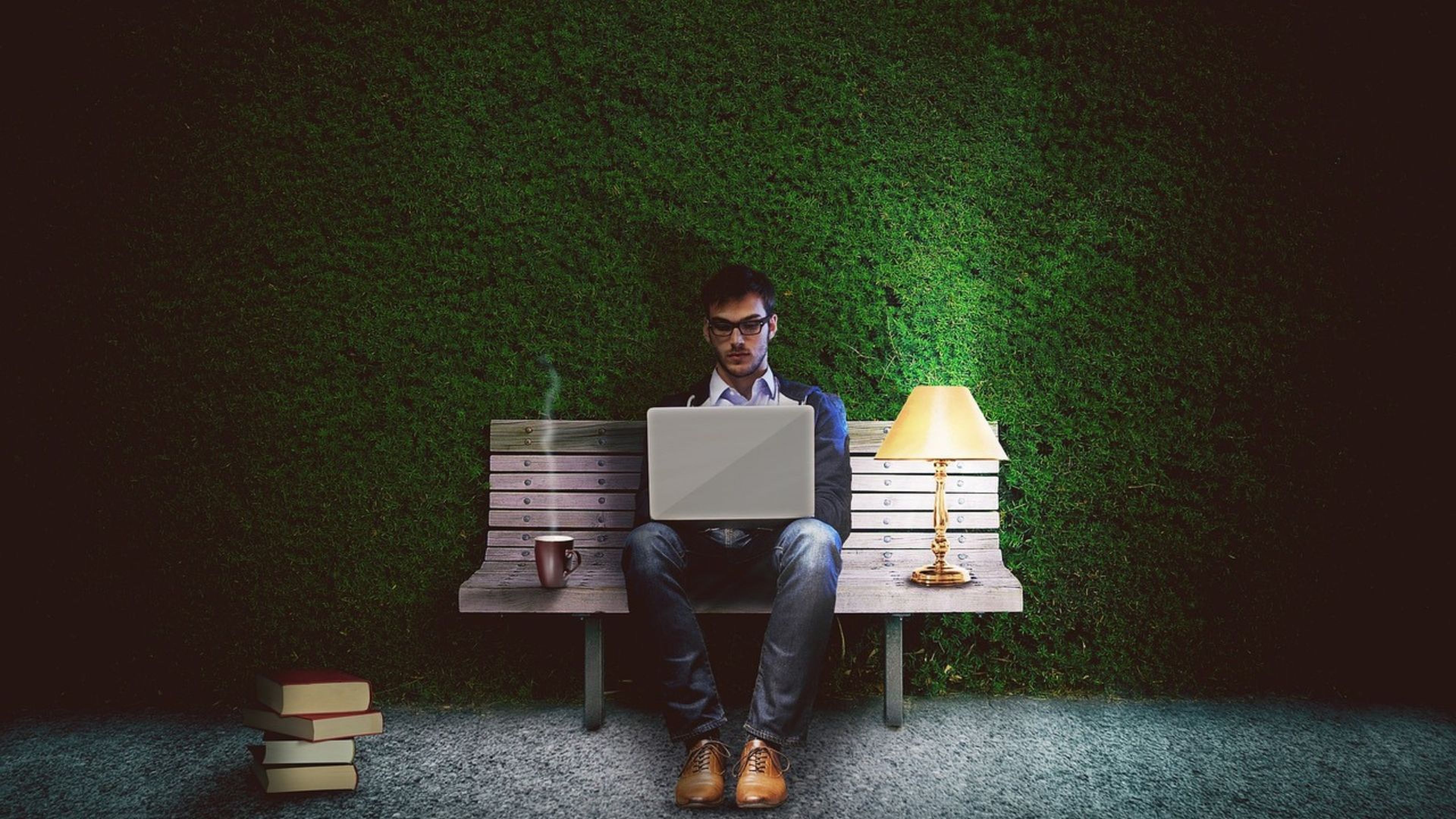 Ilustración con un señor sentado en un banco en la calle con un ordenador, un flexo y una taza de café.