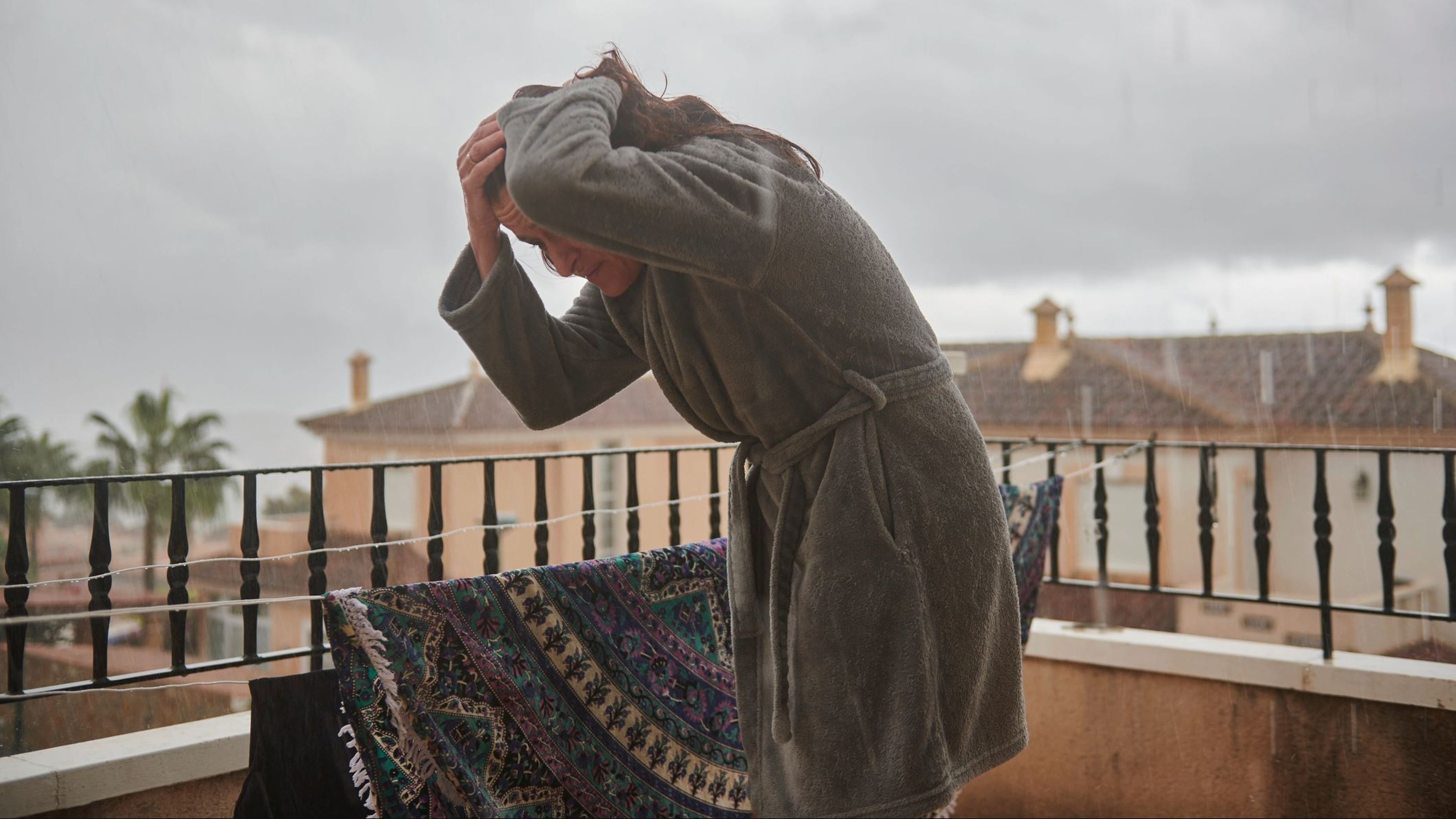 Una mujer recoge la ropa tendida, lluvia