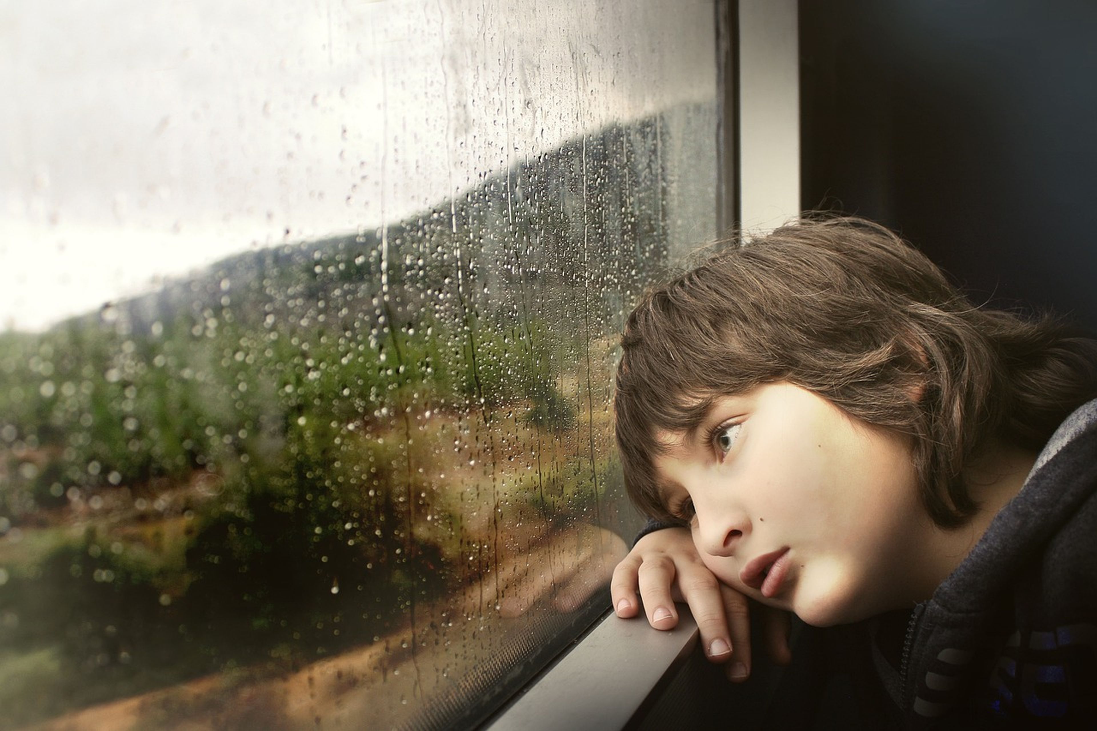 Un niño se apoya en el marco de la ventana.