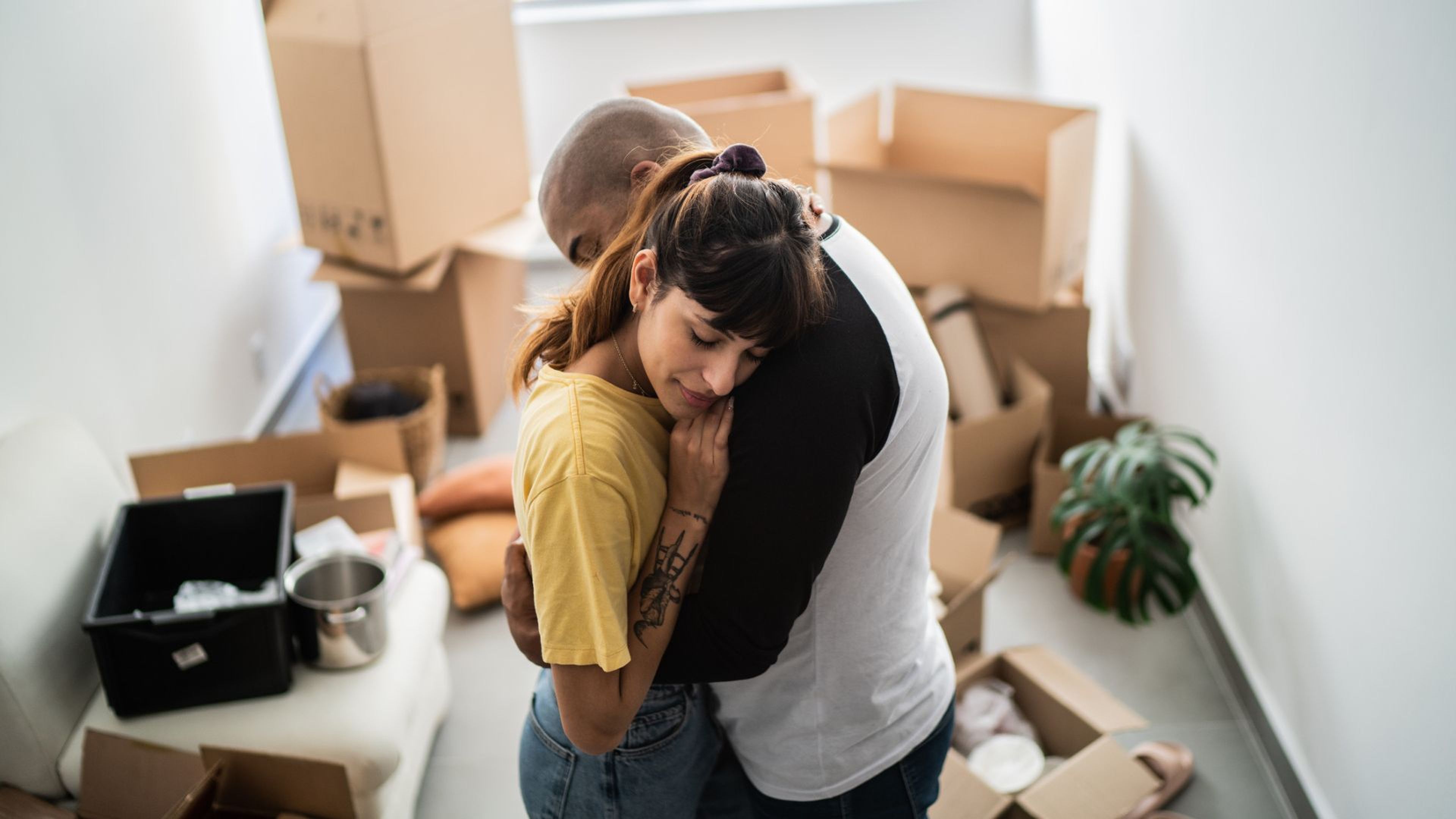 Una pareja se abraza en su casa rodeada de cajas.