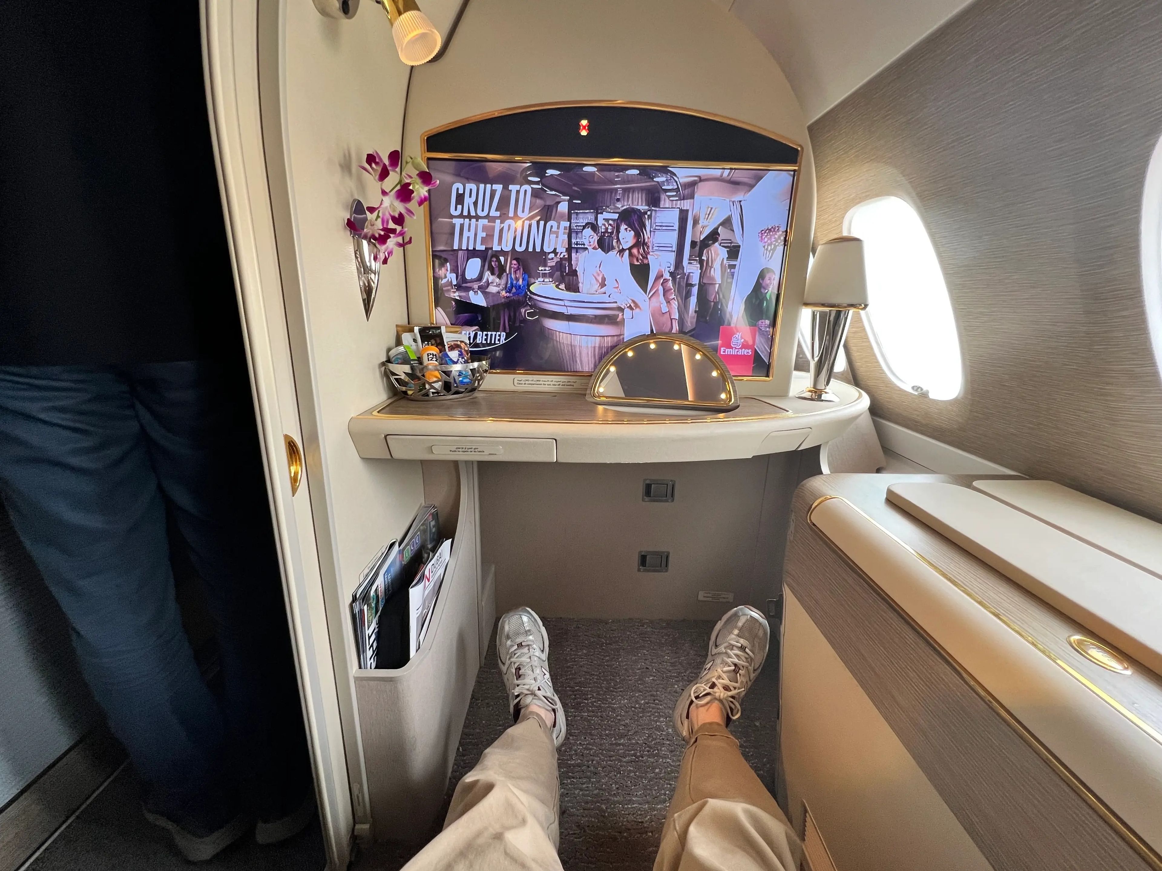 Passenger point-of-view stretching out legs in first class on Emirates A380 and TV in the background