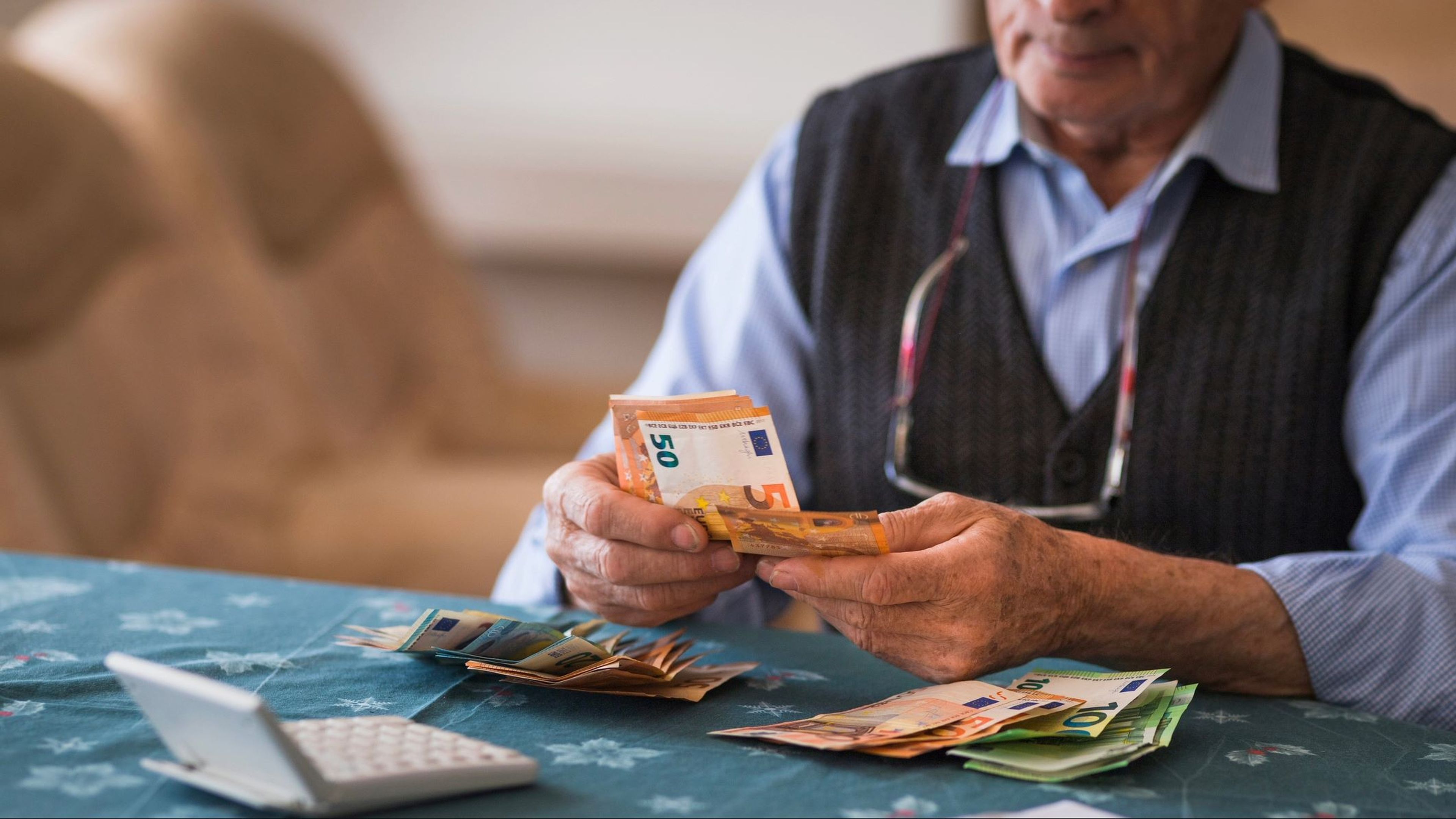 Pensionista, anciano cuenta dinero con calculadora