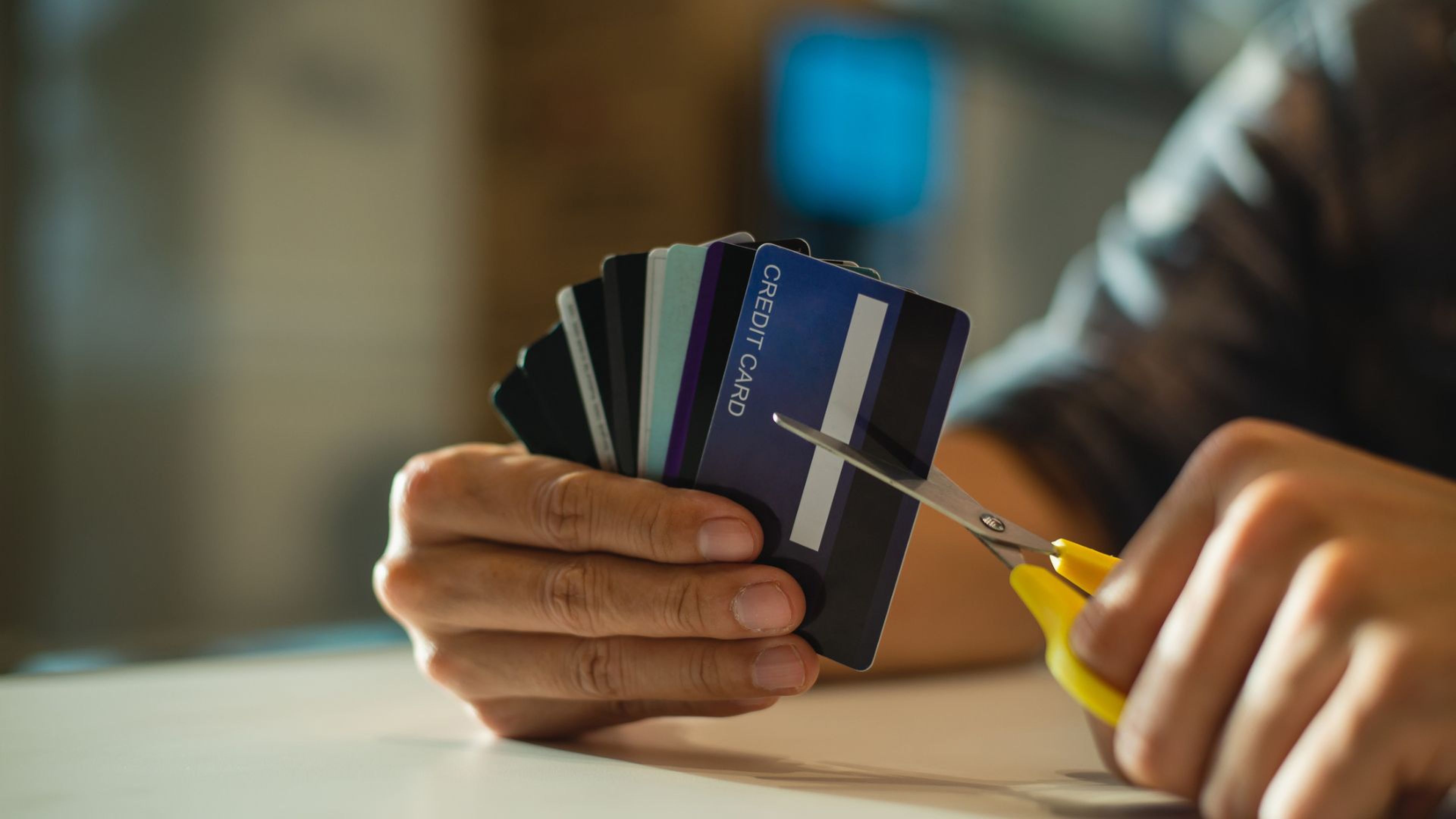 Una persona corta varias tarjetas de crédito.