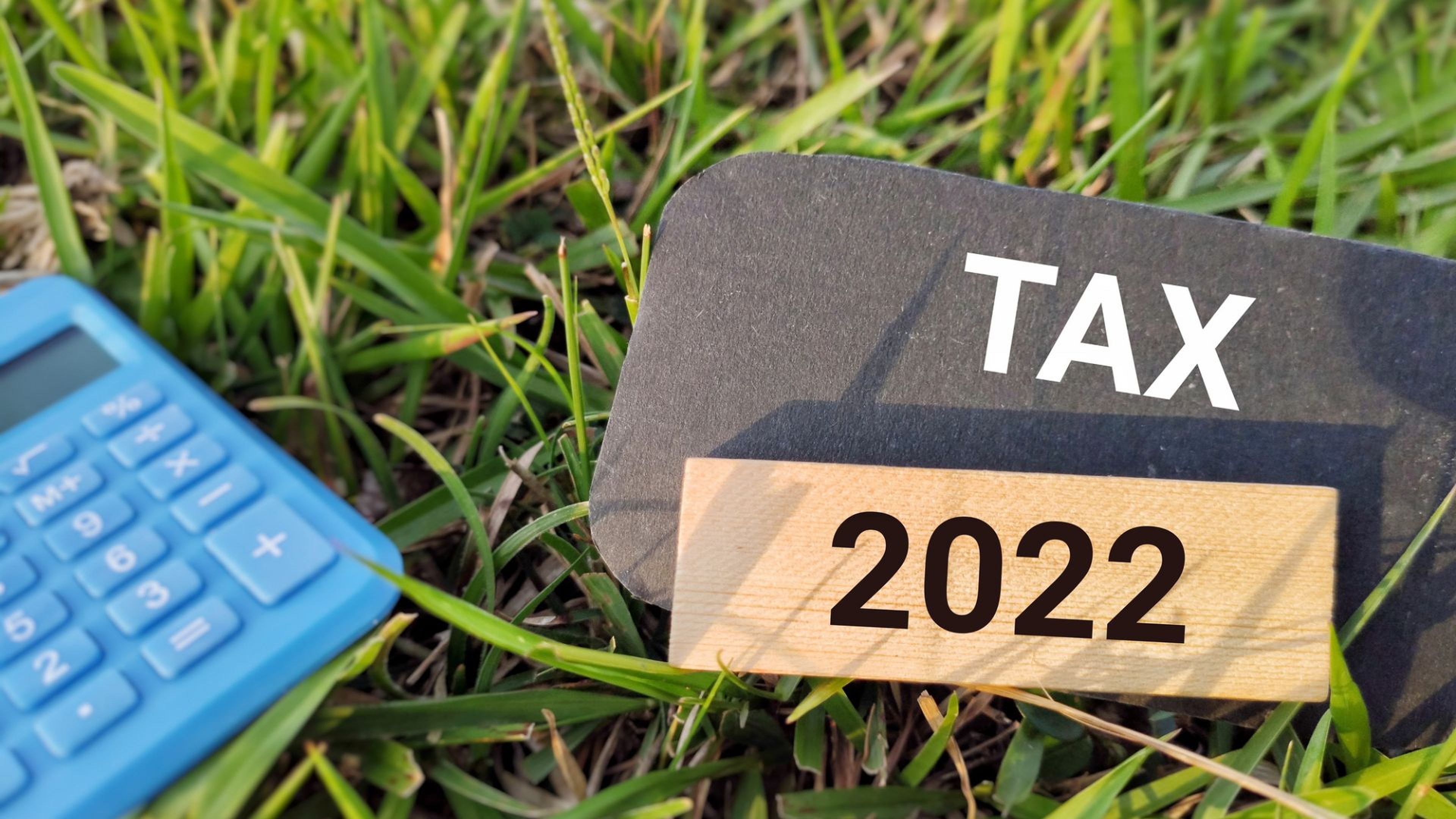 Una calculadora, un letrero en el que pone 'TAX' y unos dados con el año 2022.