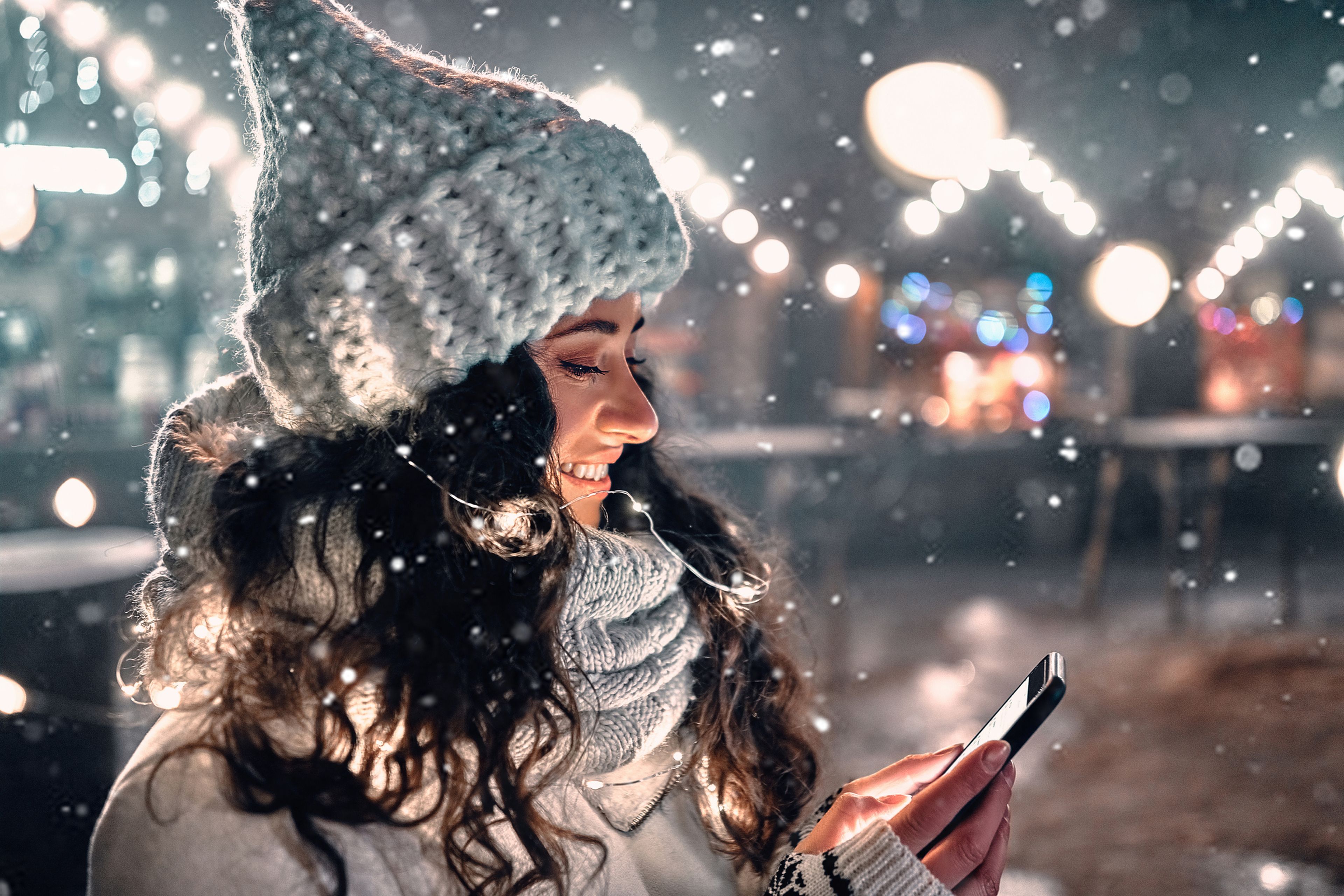 Chica en Navidad con el móvil mientras nieva