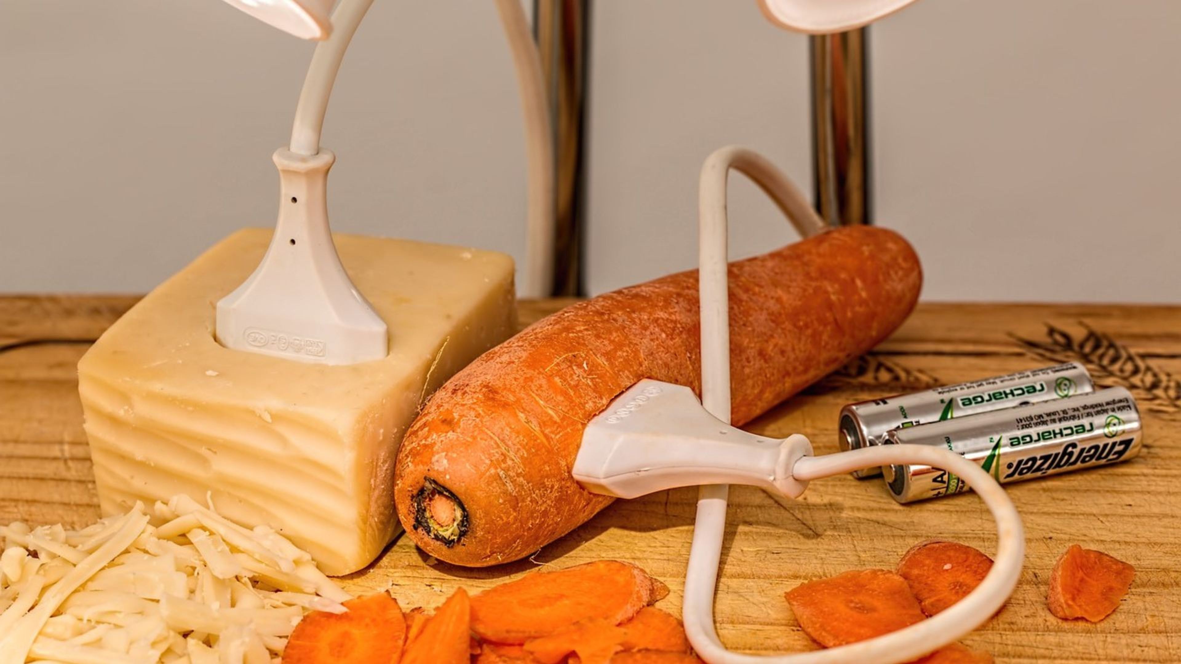 Un enchufe enchufado en una zanahoria y otro en un trozo de queso.