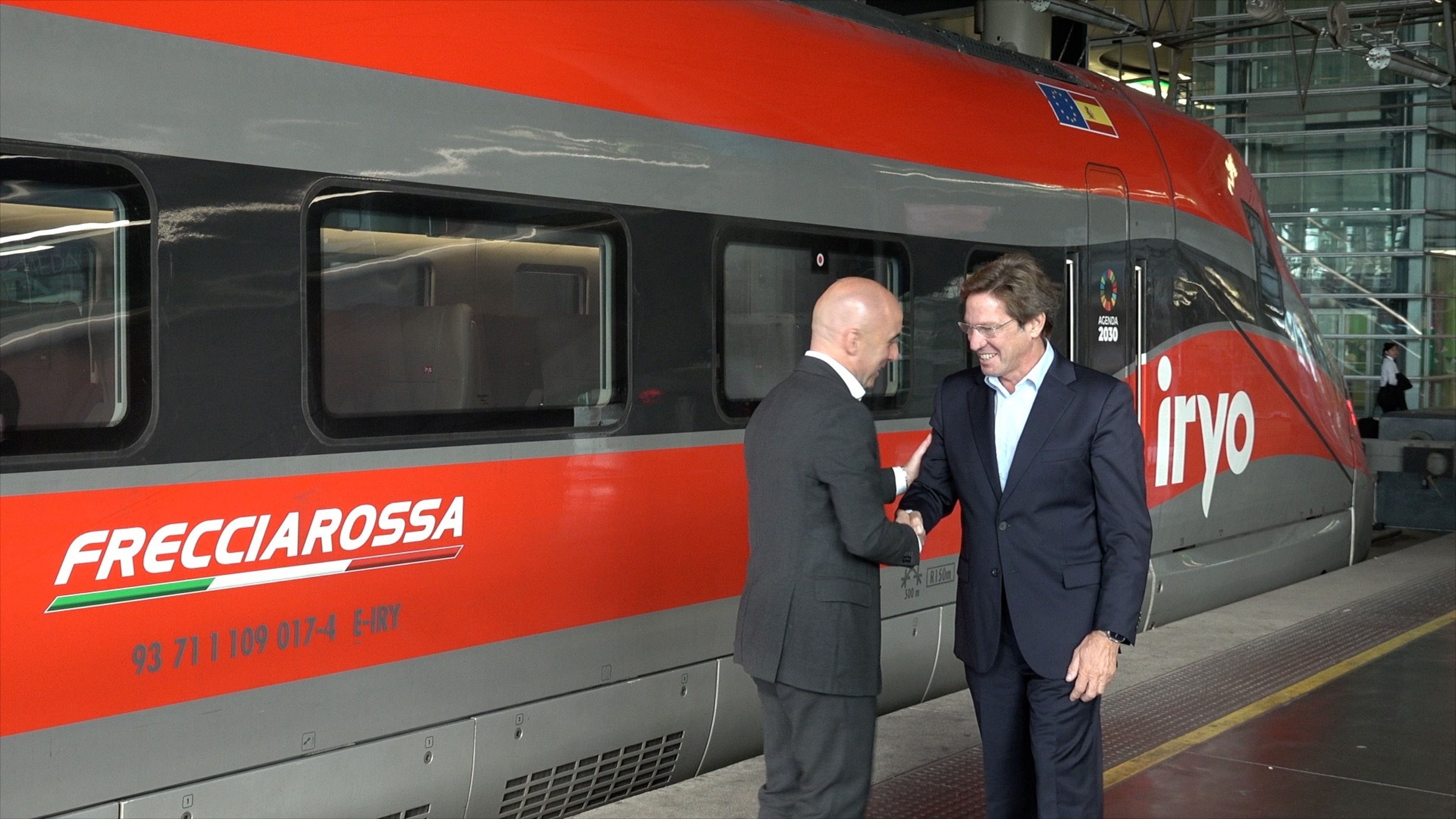 Joan Jordi Vallverdú y Simone Gorini se saludan frente a uno de los trenes de iryo.