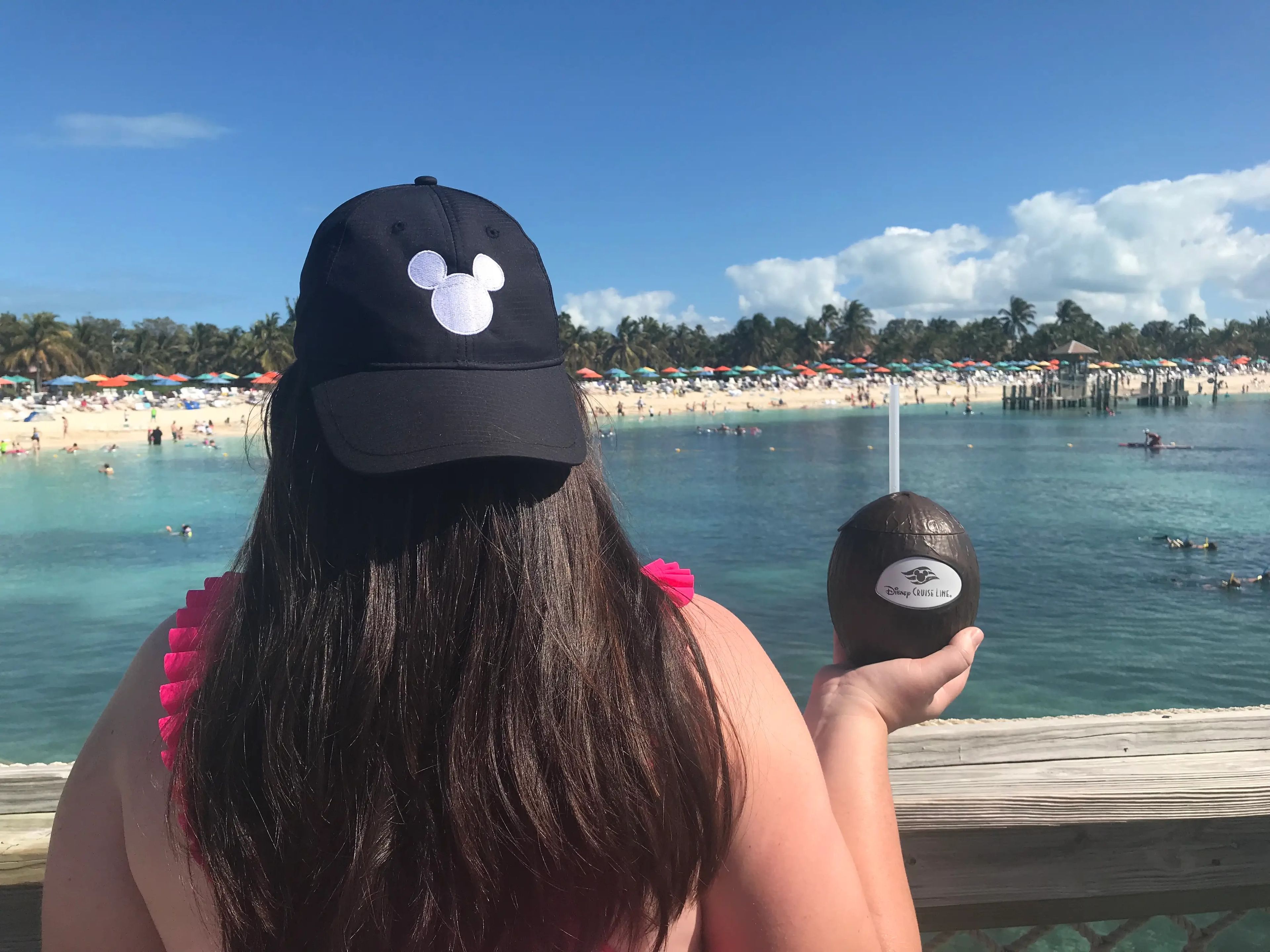 Megan DuBois, author, in a mickey baseball cap with a coconut drink looking out into Castaway Cay
