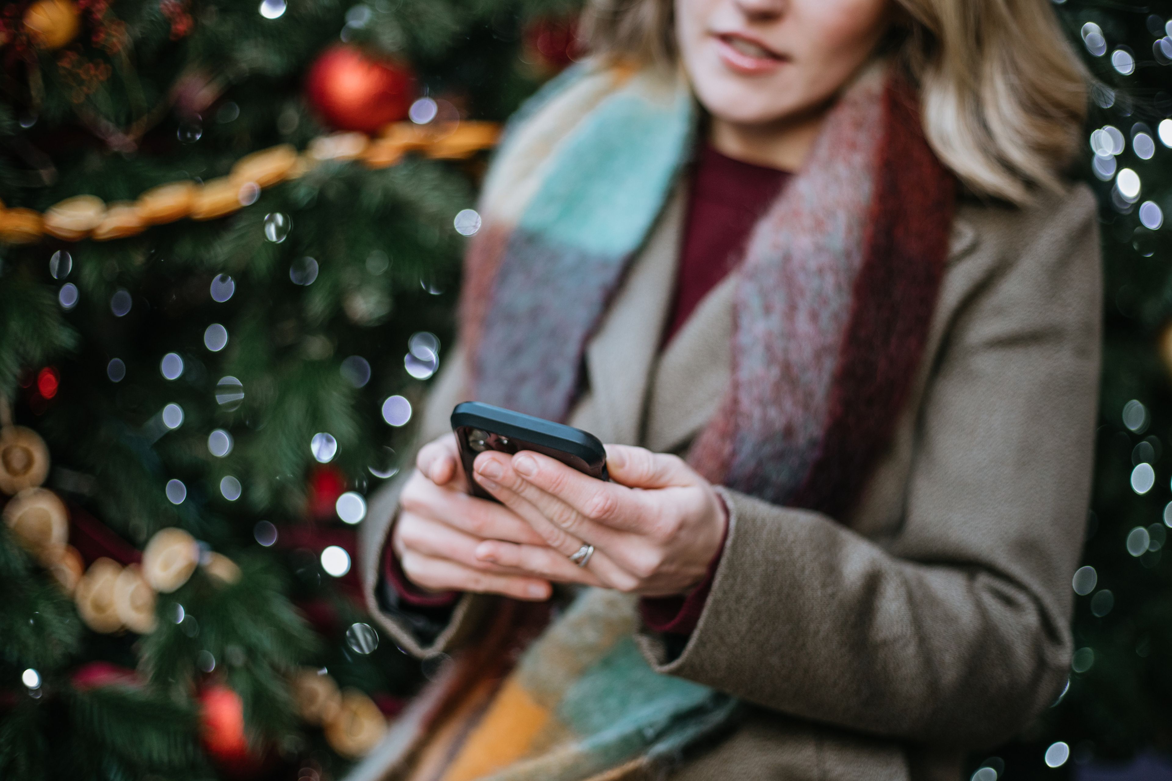 Mujer con un móvil con un árbol de navidad de fondo