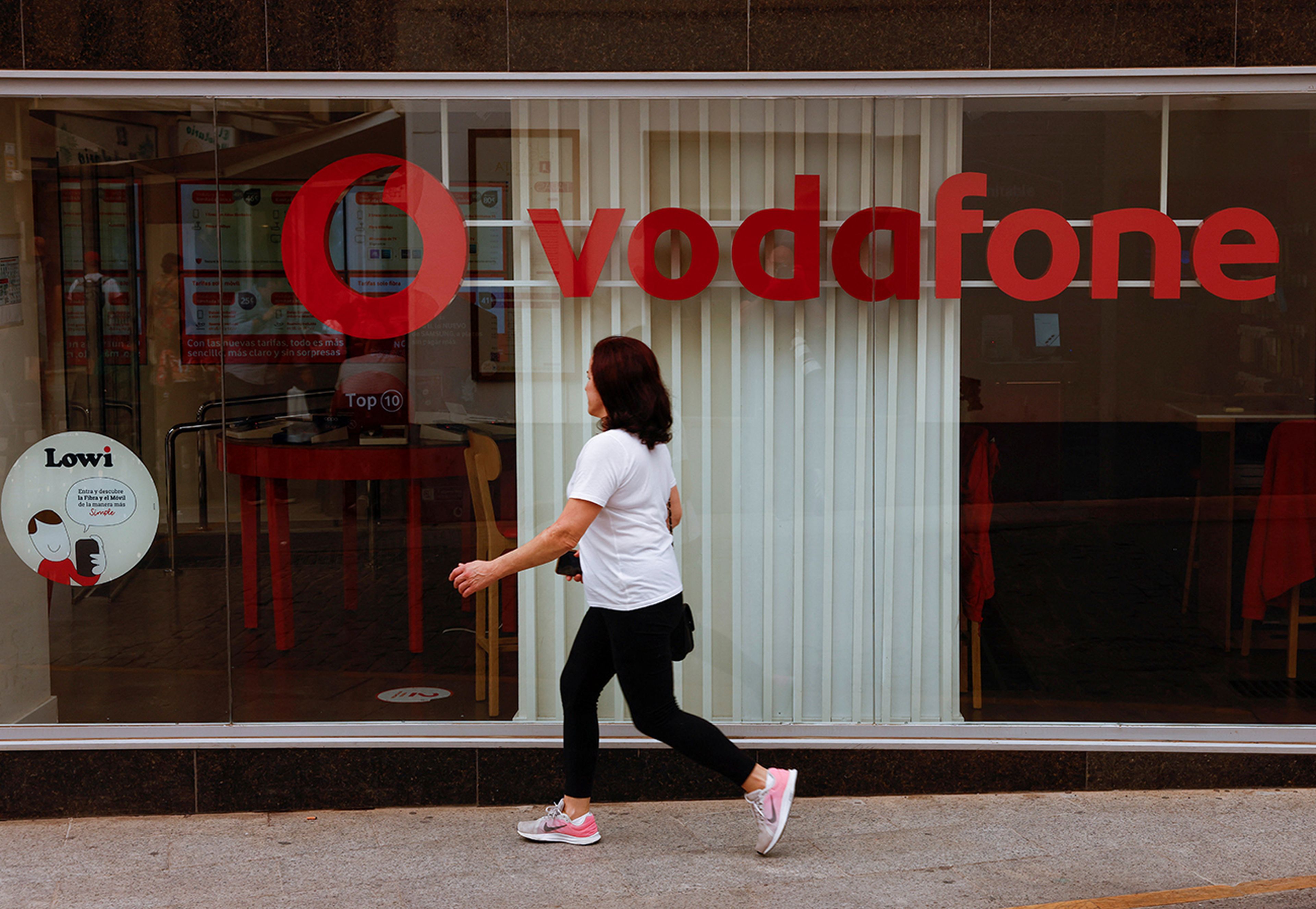 Mujer paseando frente a escaparate de Vodafone