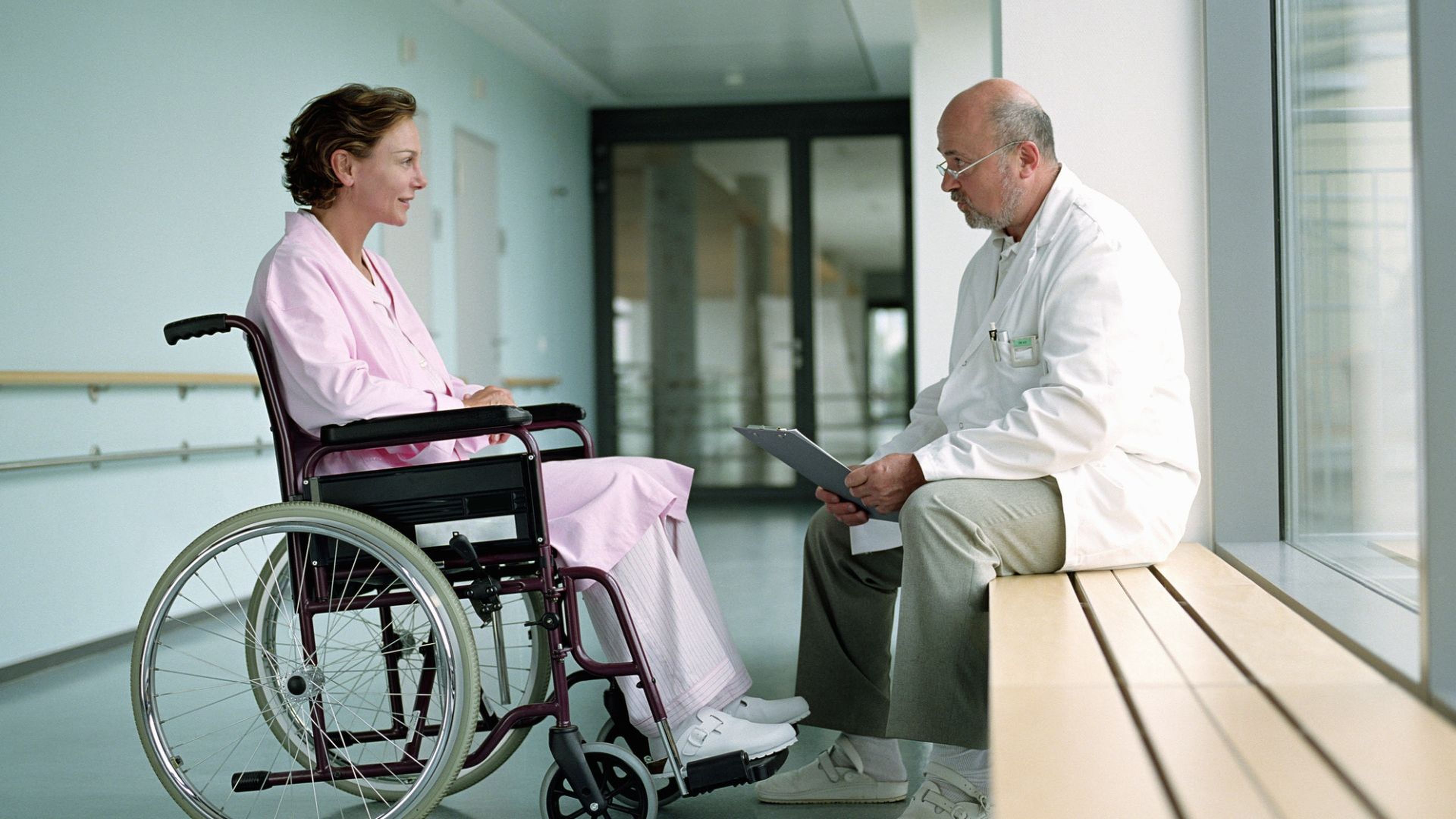 Una mujer en silla de ruedas habla con el médico.