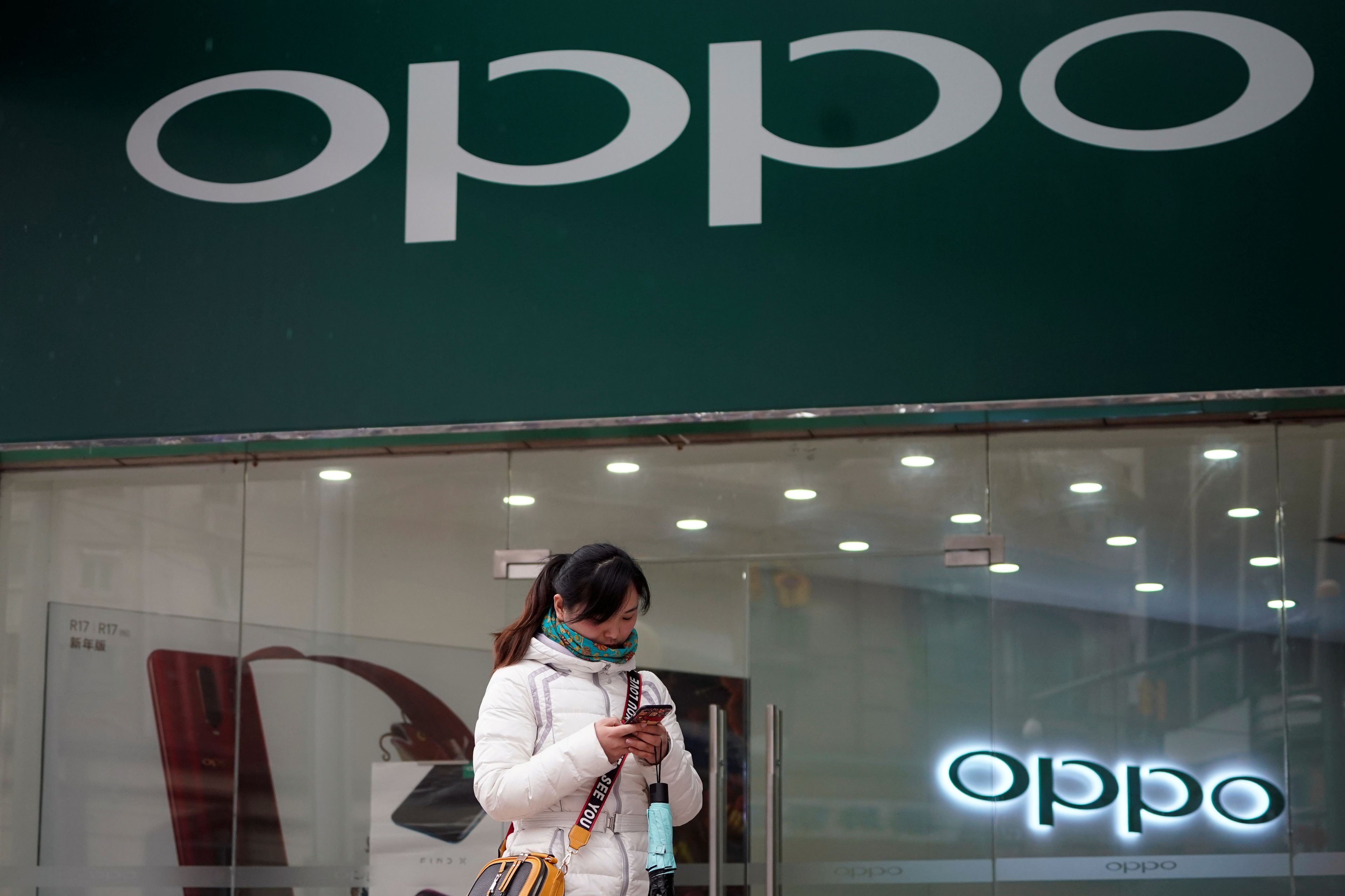 Una persona frente a una tienda con un logo de Oppo