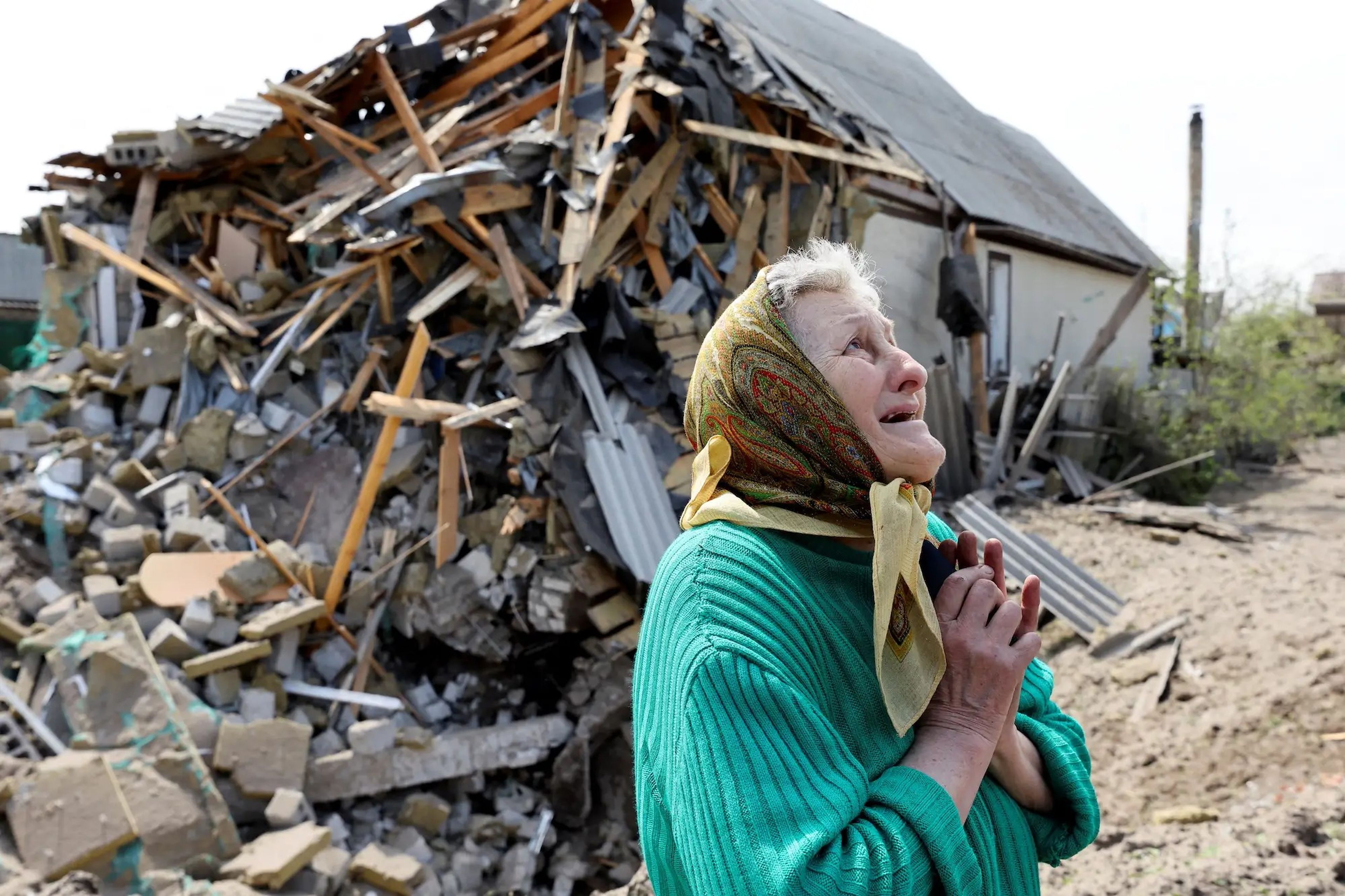Una mujer delante de una casa cercana a la suya que fue destruida por un misil en Lyman, en la región ucraniana de Donetsk, en abril de 2022. 