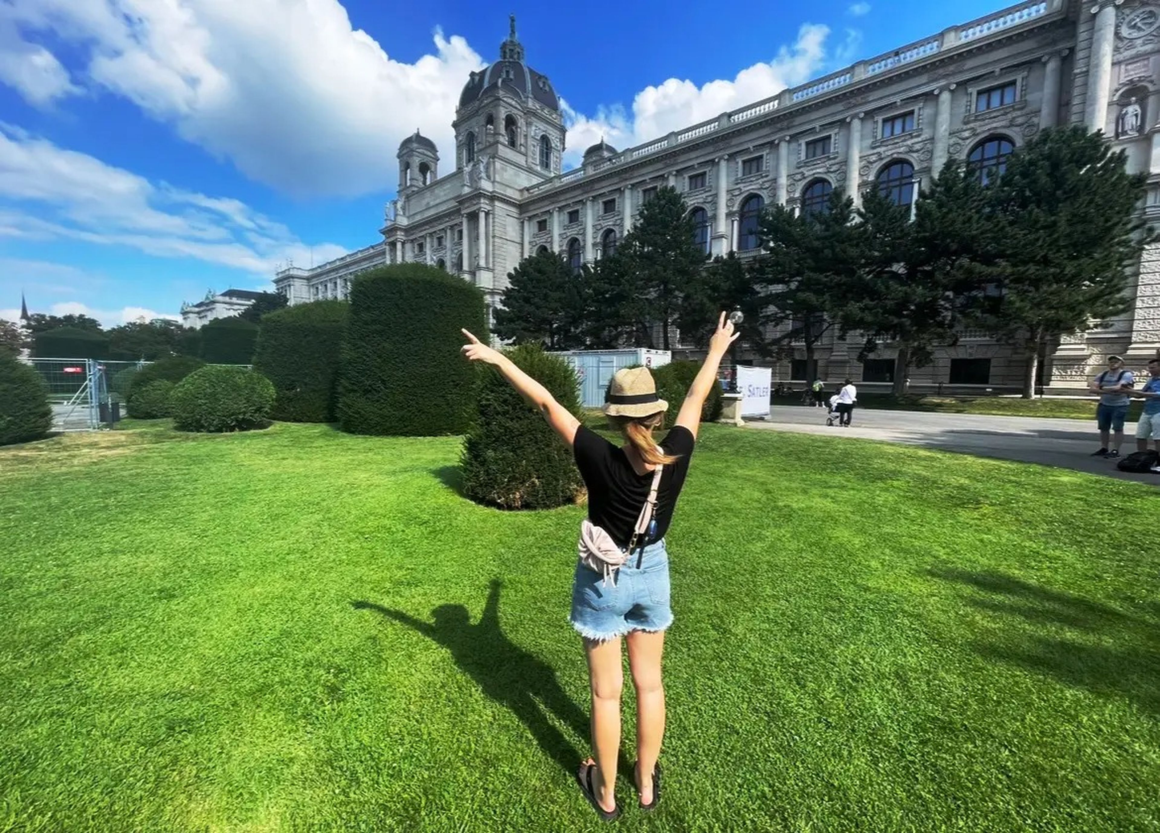 Author Hayley Domin with her arms raised in front of a landmark