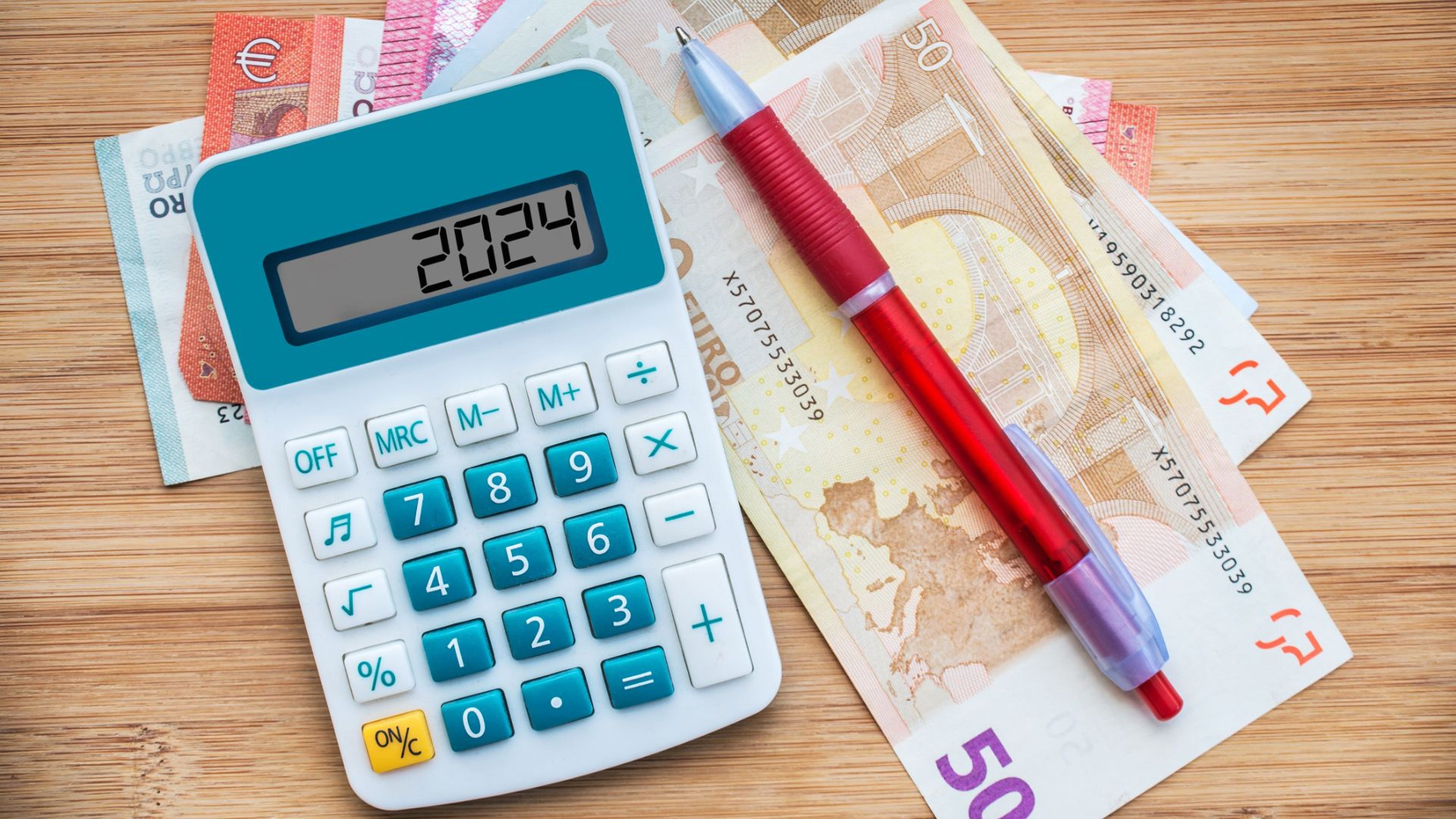 Una calculadora con el número 2024, un bolígrafo y varios billetes de euros.