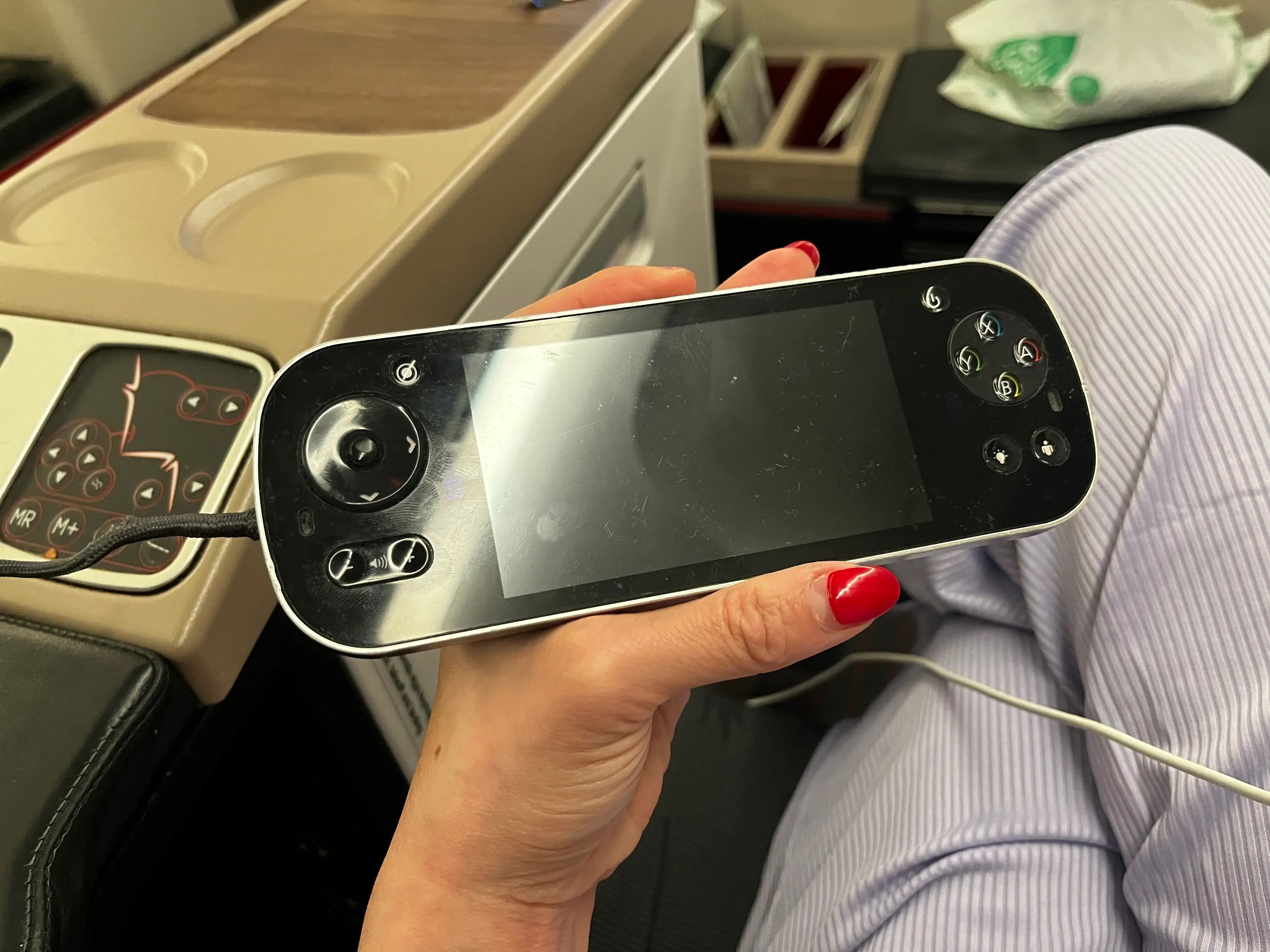A hand holds a black game controller on a Turkish Airlines flight