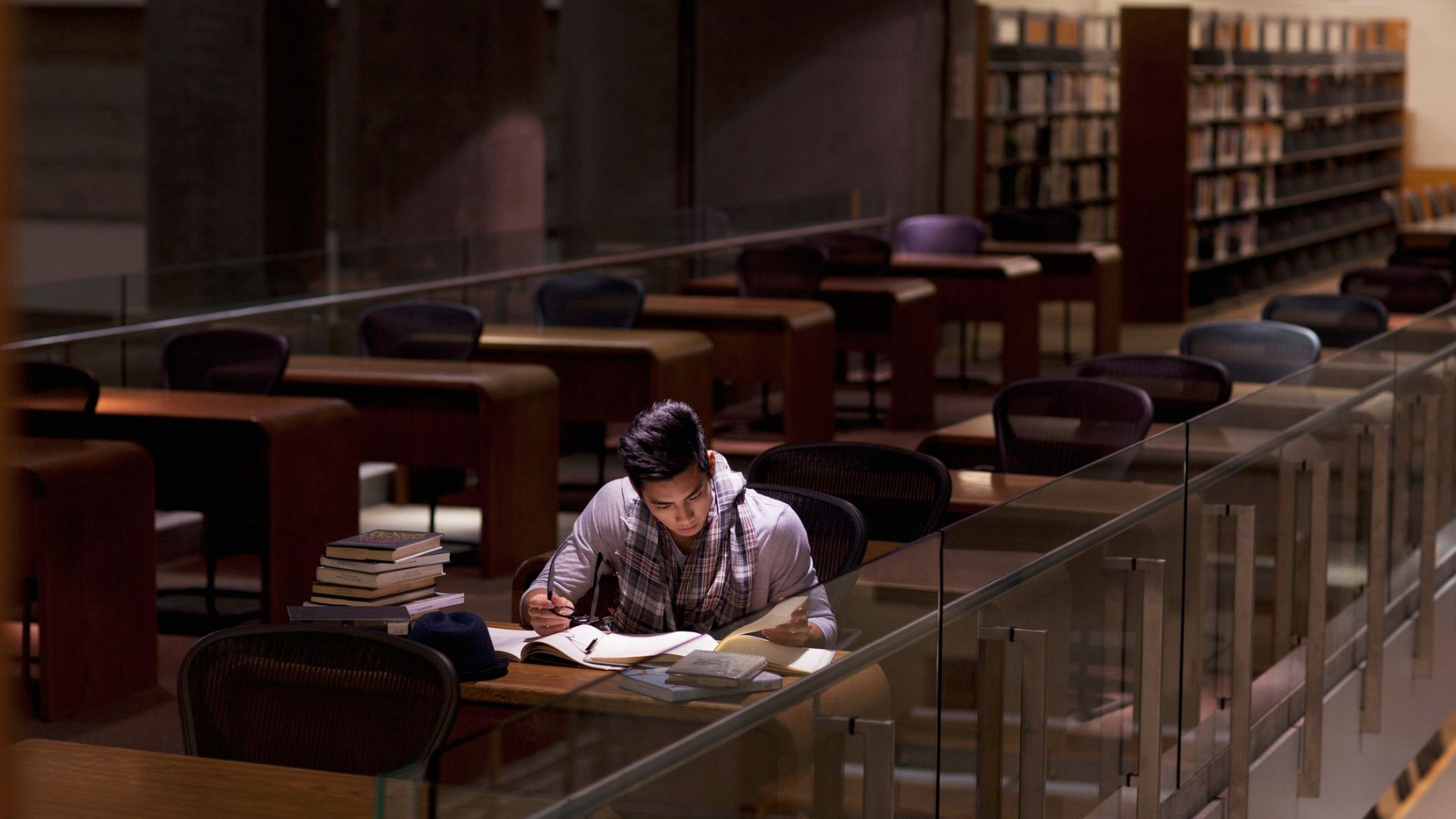 Un joven estudia en una biblioteca.