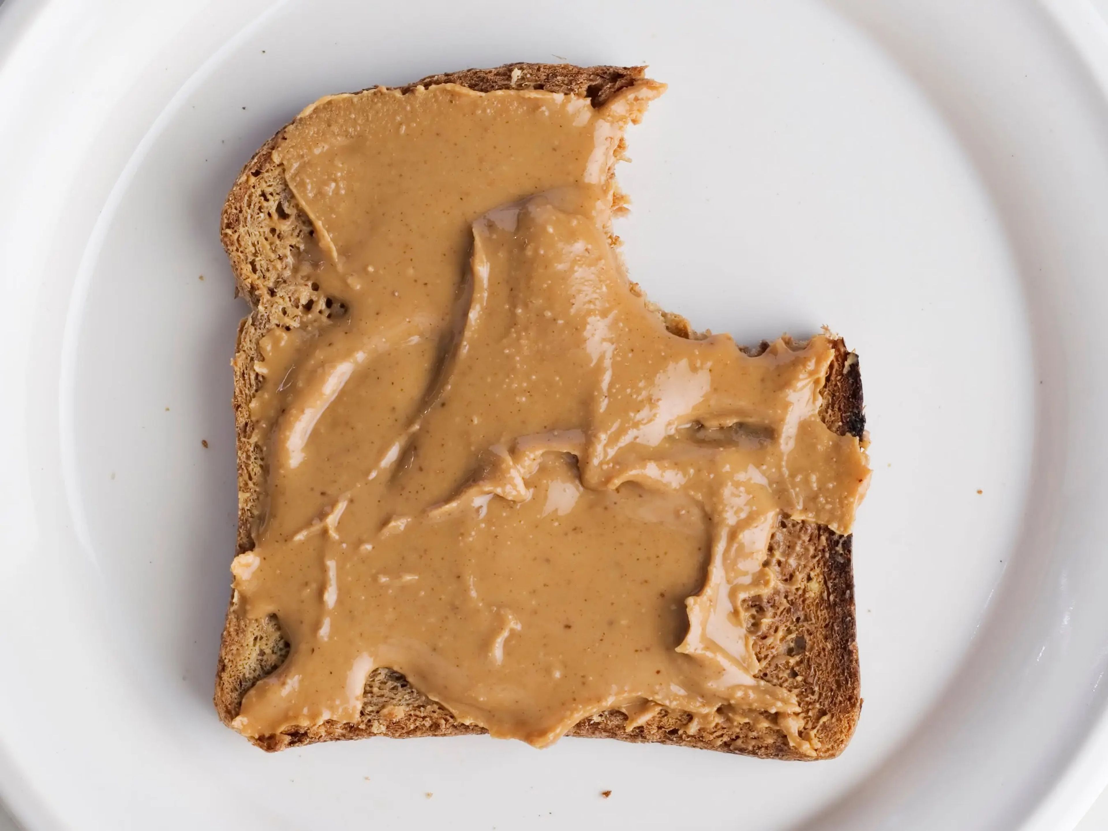 Cubre tu tostada de pan integran con mantequilla de cacahuete.