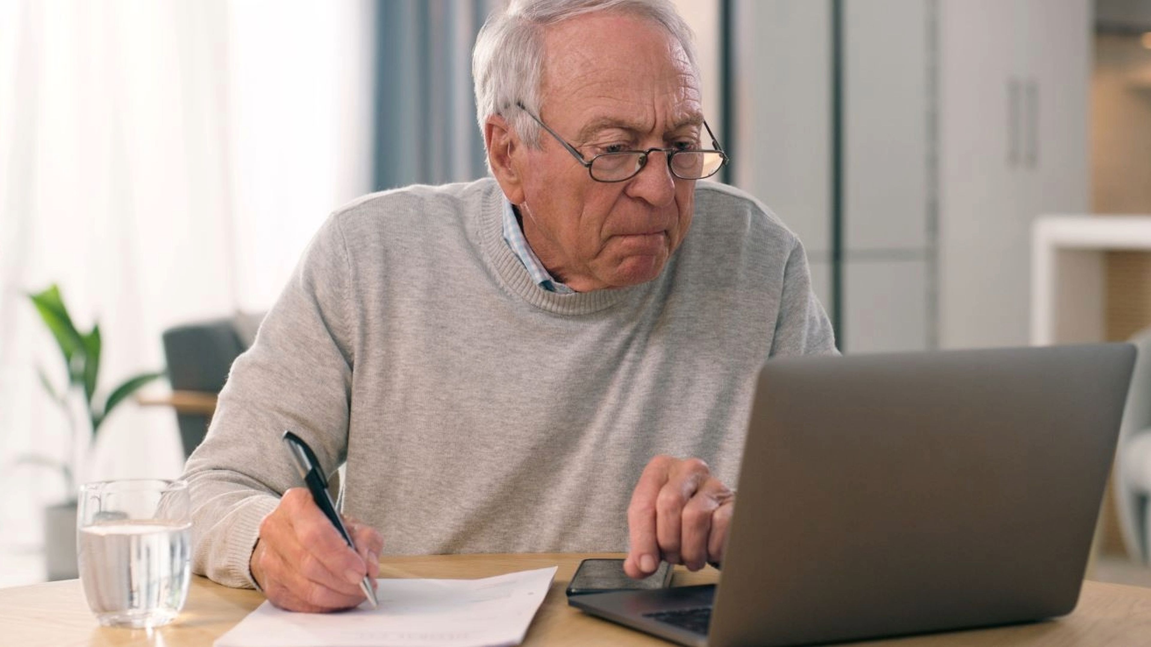 Pensionista concentrado, documentos, ordenador