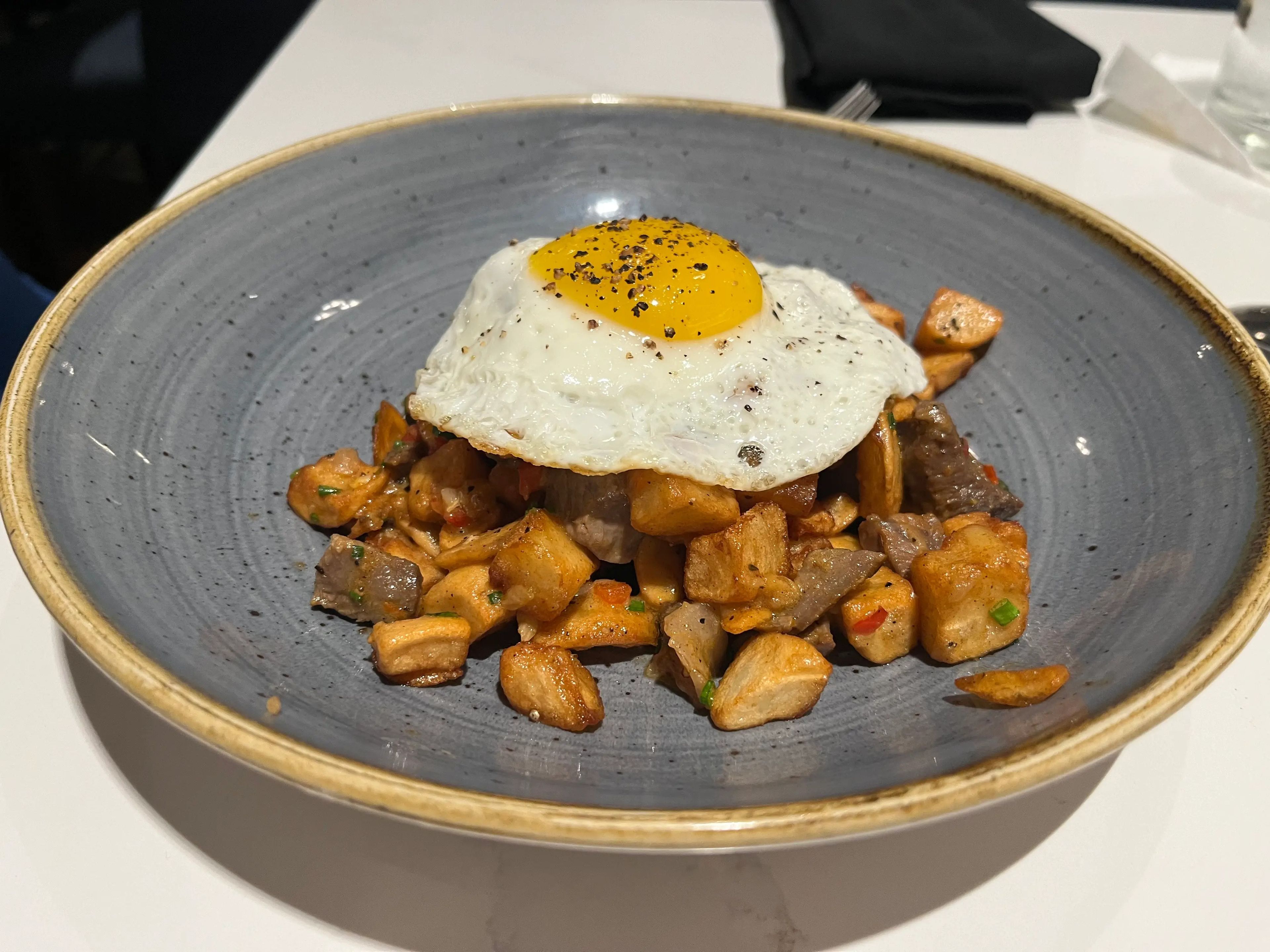 plate of breakfast potatoes topped with a fried egg from steakhouse 71 at disney world