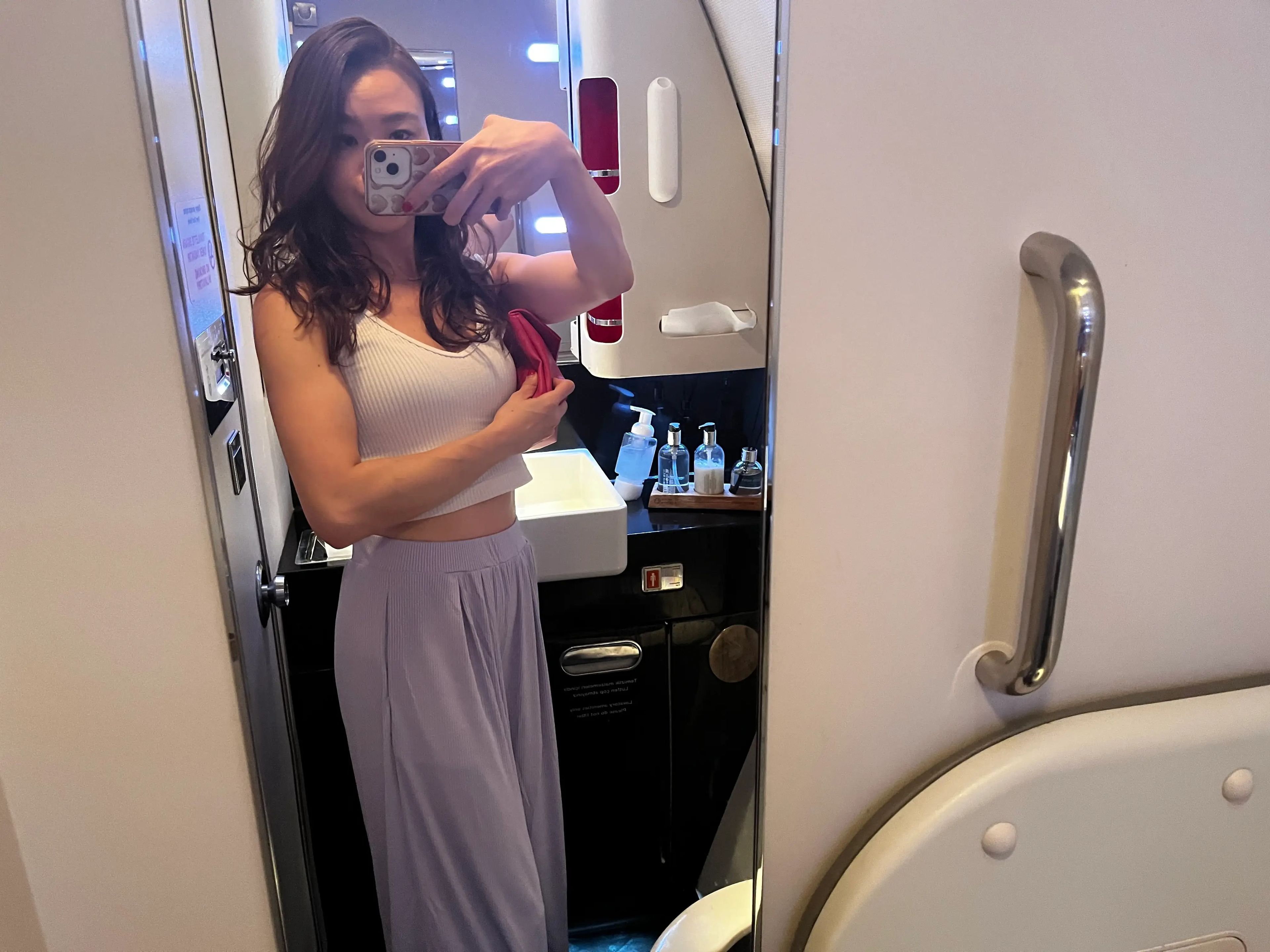 Selfie of the writer in white shirt and purple pants in bathroom area of Turkish Airlines flight