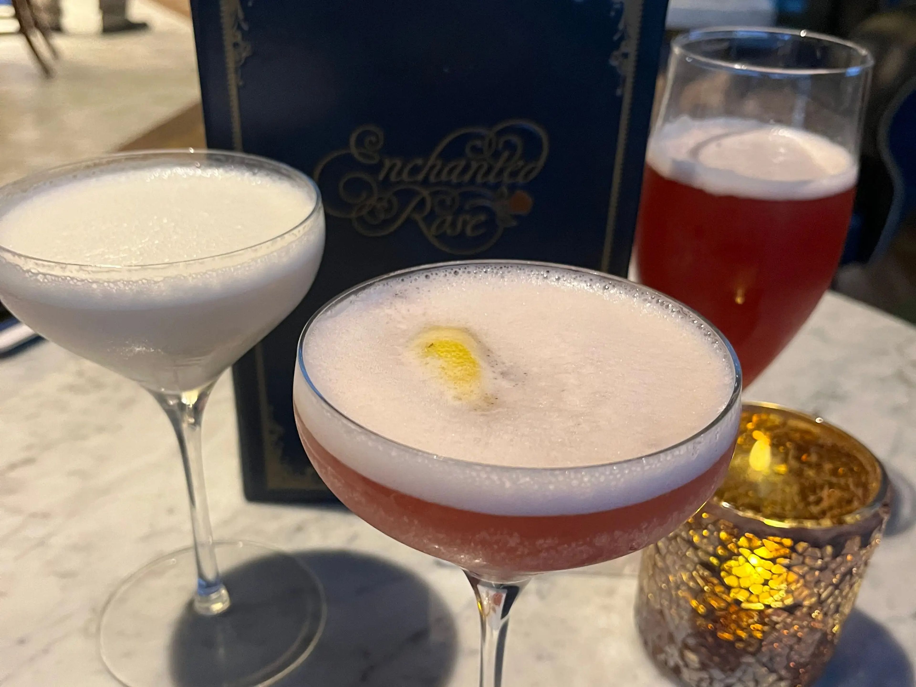 three cocktails on a table at the enchanted rose in the grand floridian in disney world