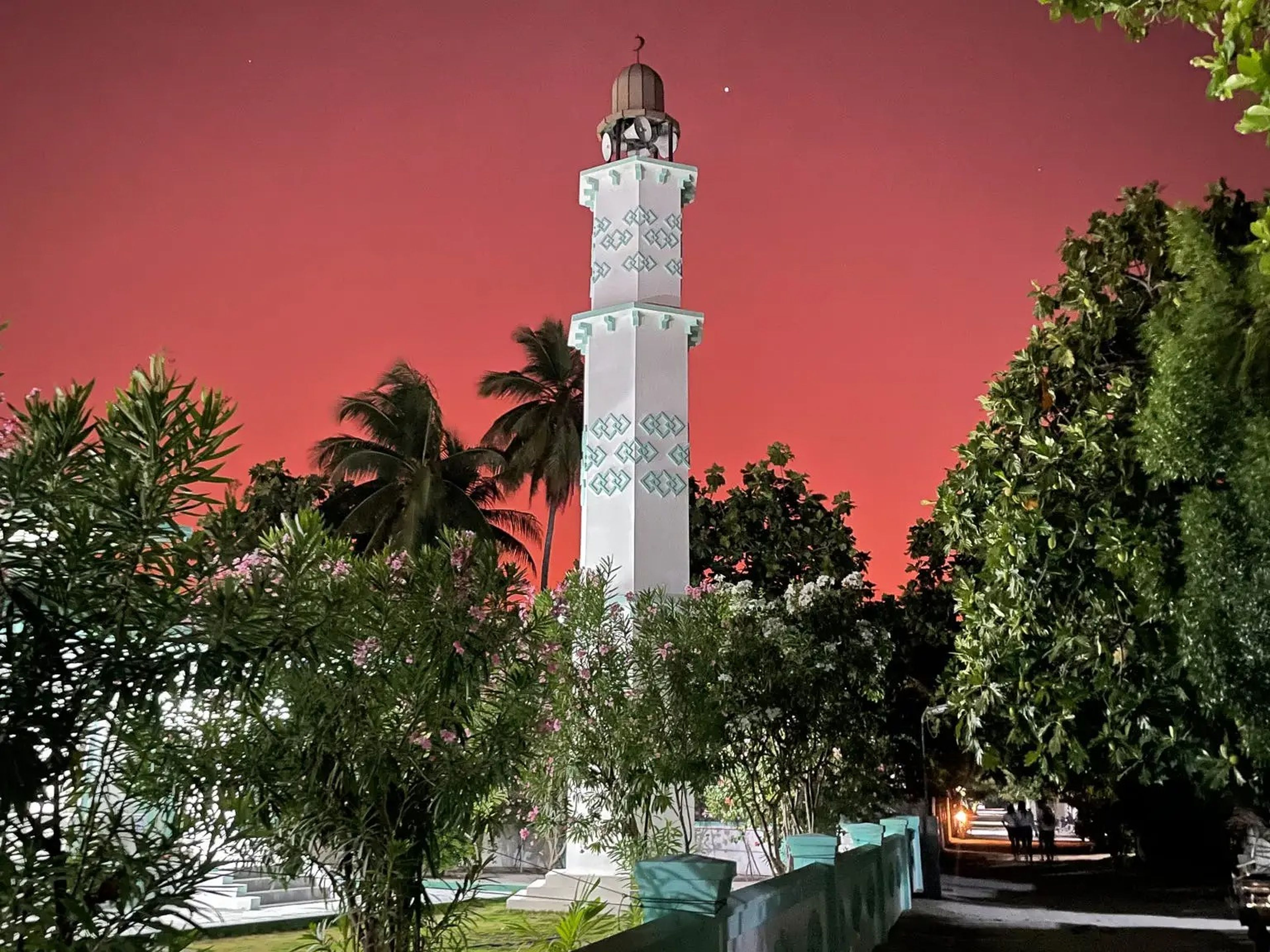 A white mosque with turquoise detailing at sunset.