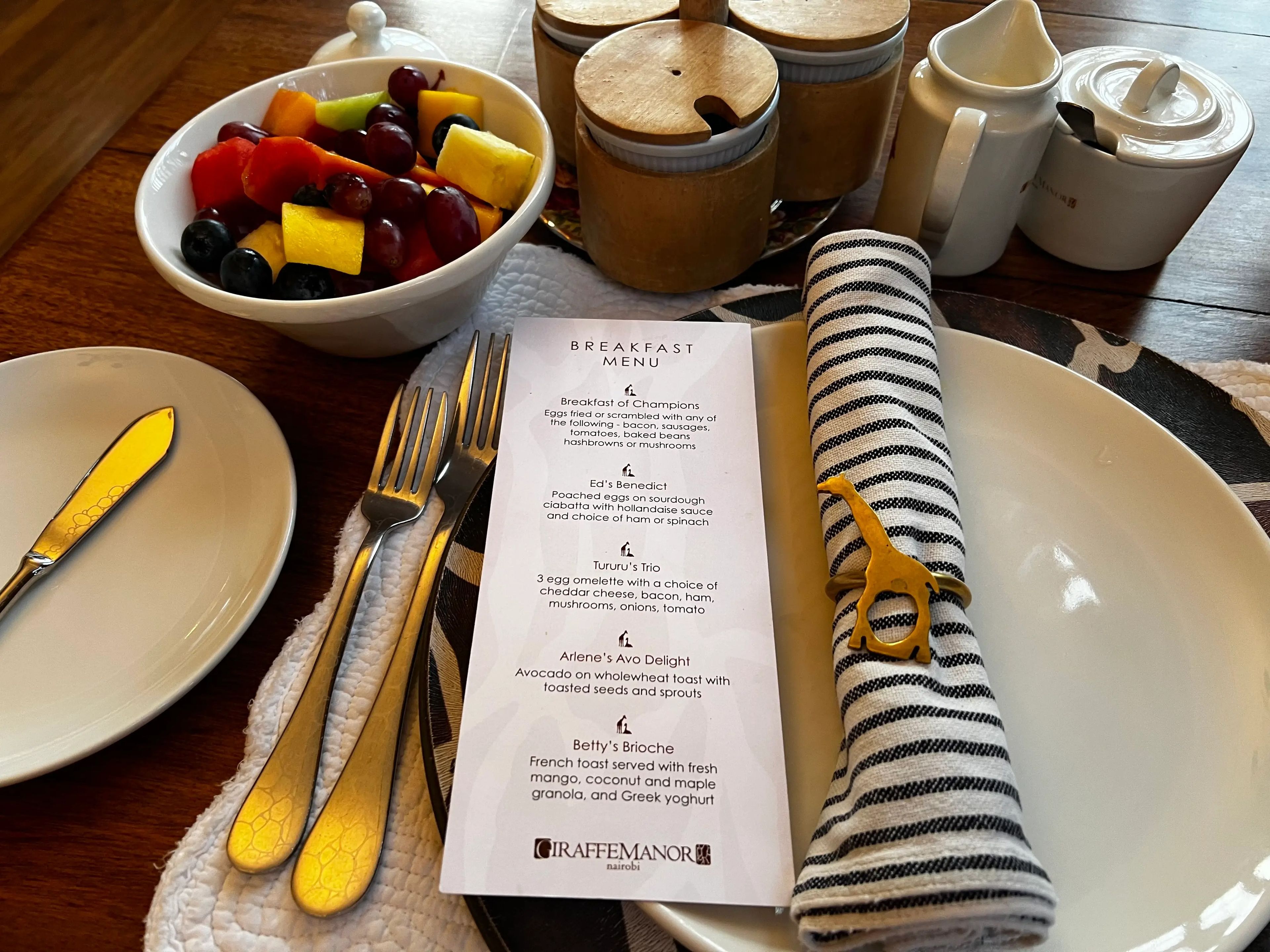 Breakfast menu next to gold silverware and giraffe napkin ring 