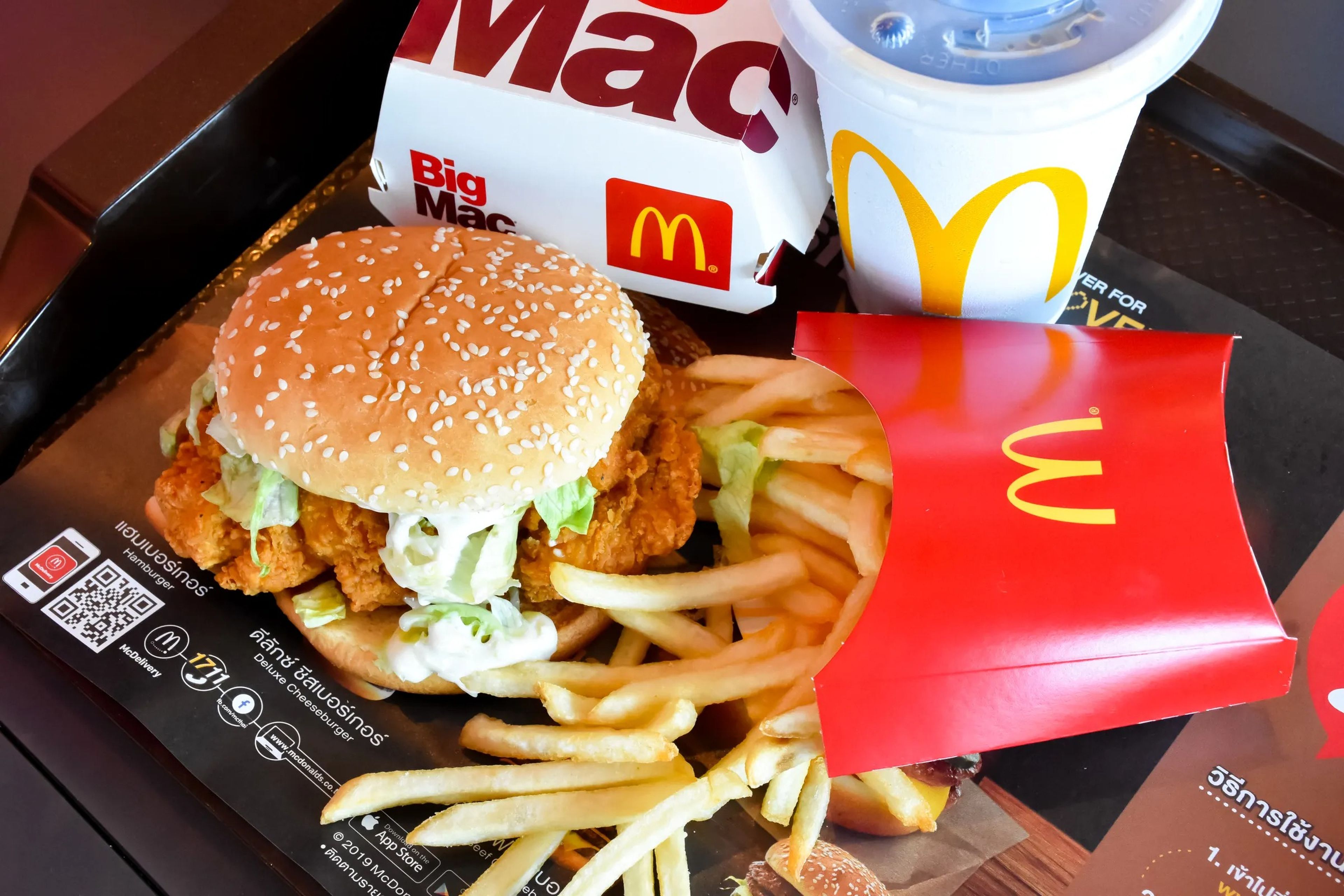 A chicken sandwich, french fries, a Big Mac box, and a soda on a tray.