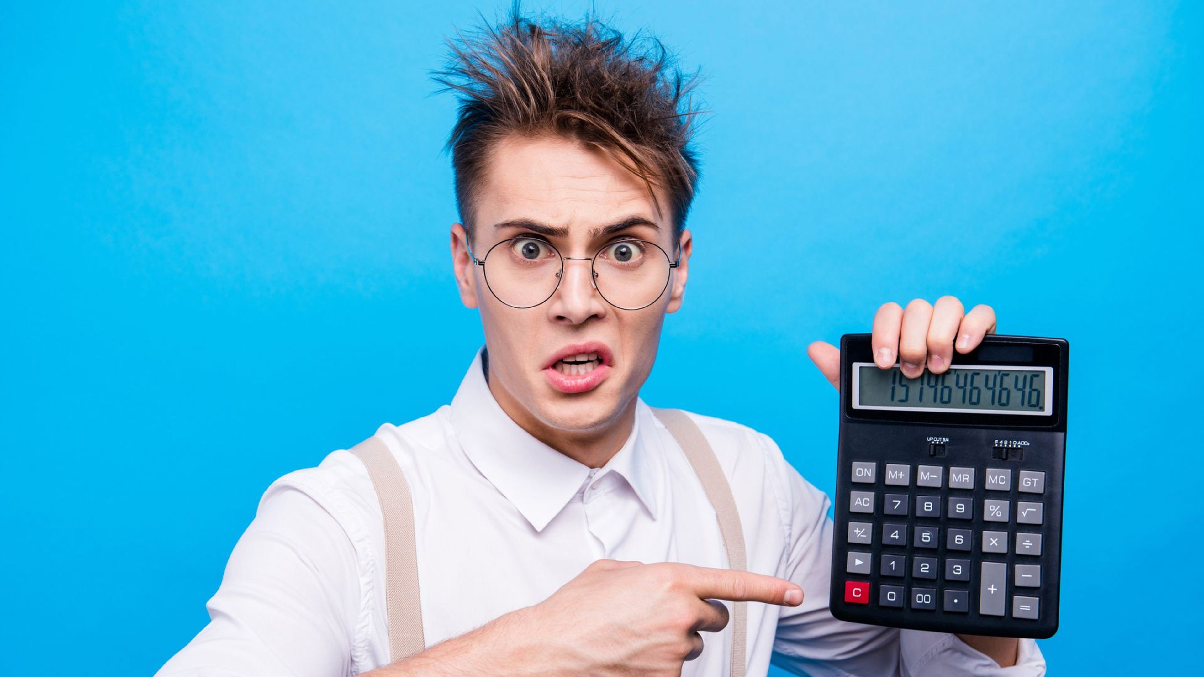 Un chico con cara de enfado y una calculadora en la mano.