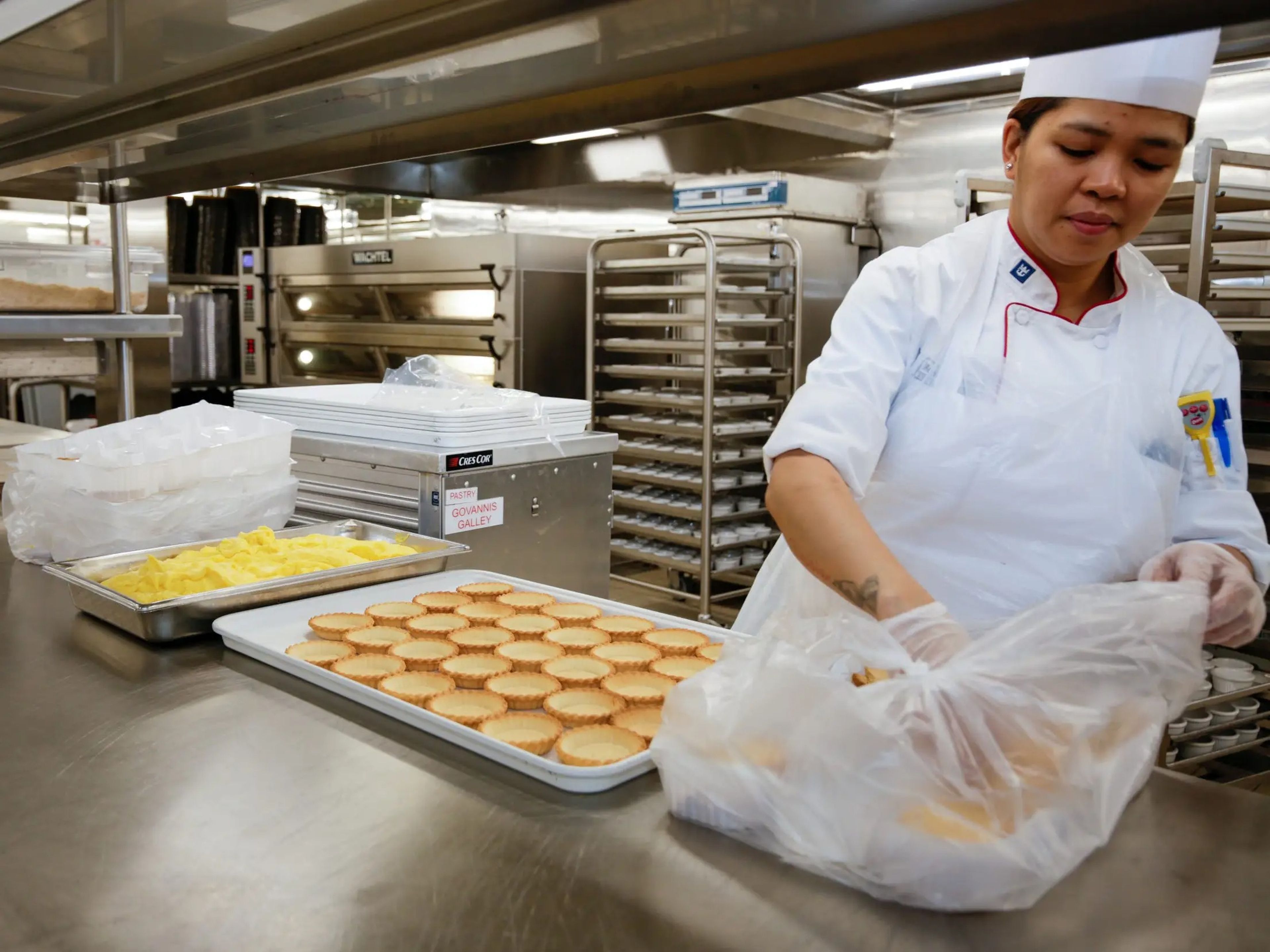 cook preparing food on trays on Royal Caribbean's Icon of the Seas