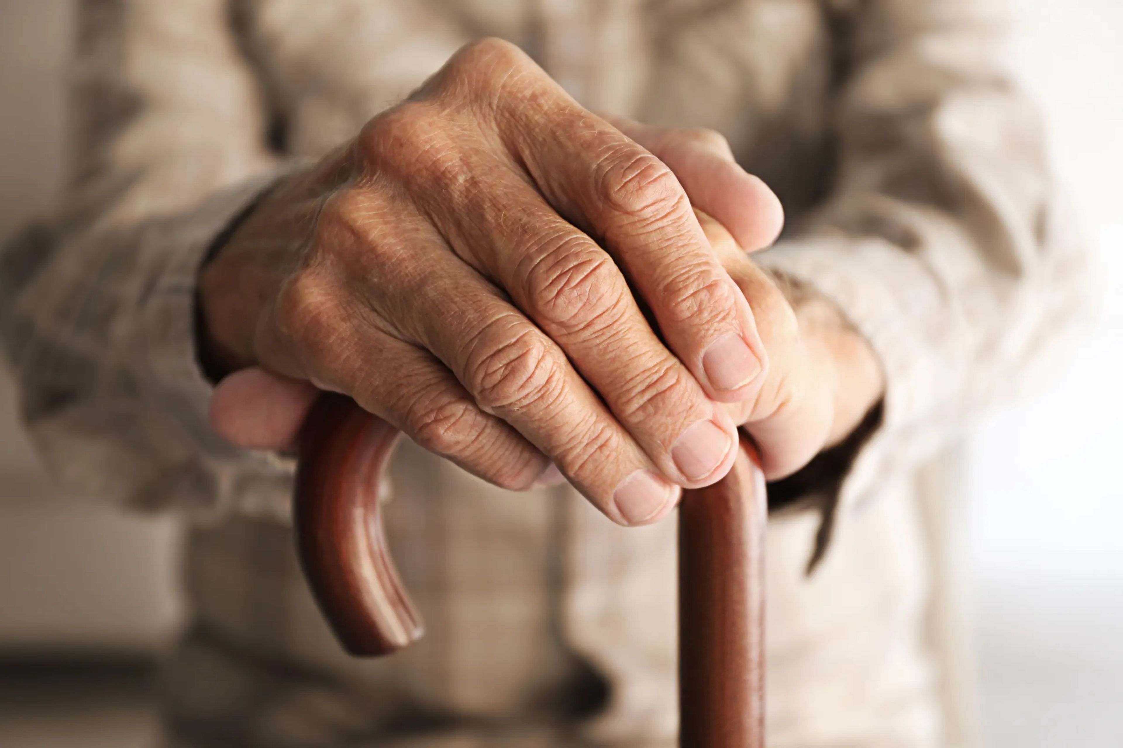 Elderly man's hands holding a cane