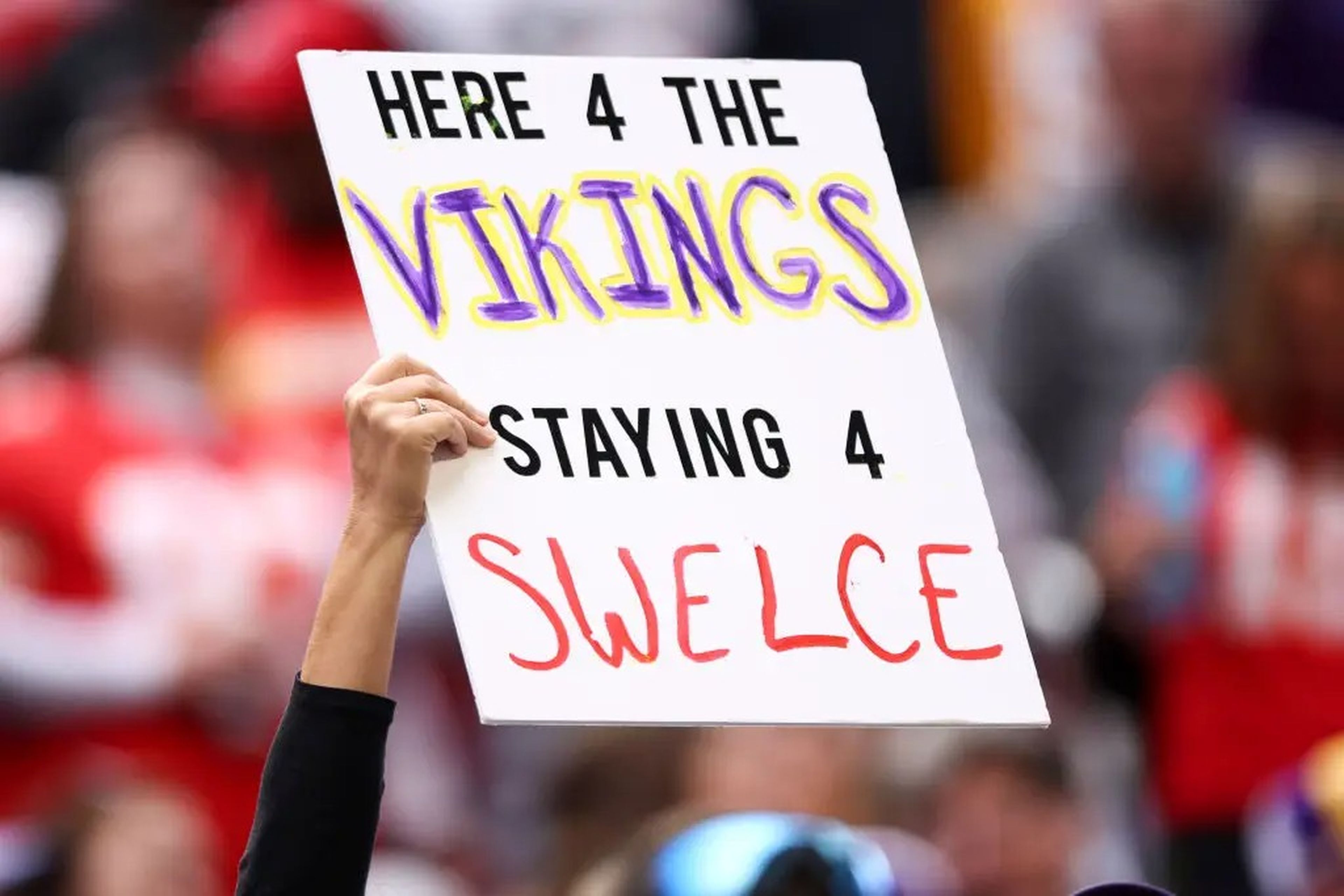 A fan holding up a "Swelce" sign at a football game.