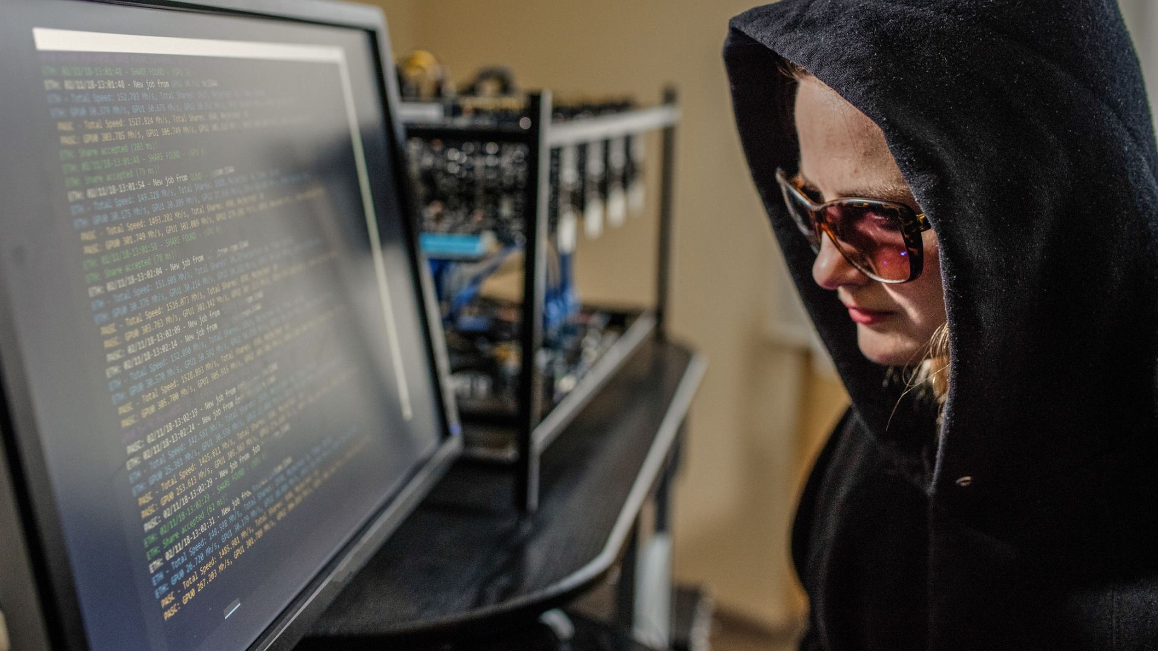 Una 'hacker' con capucha y gafas de sol delante del ordenador.