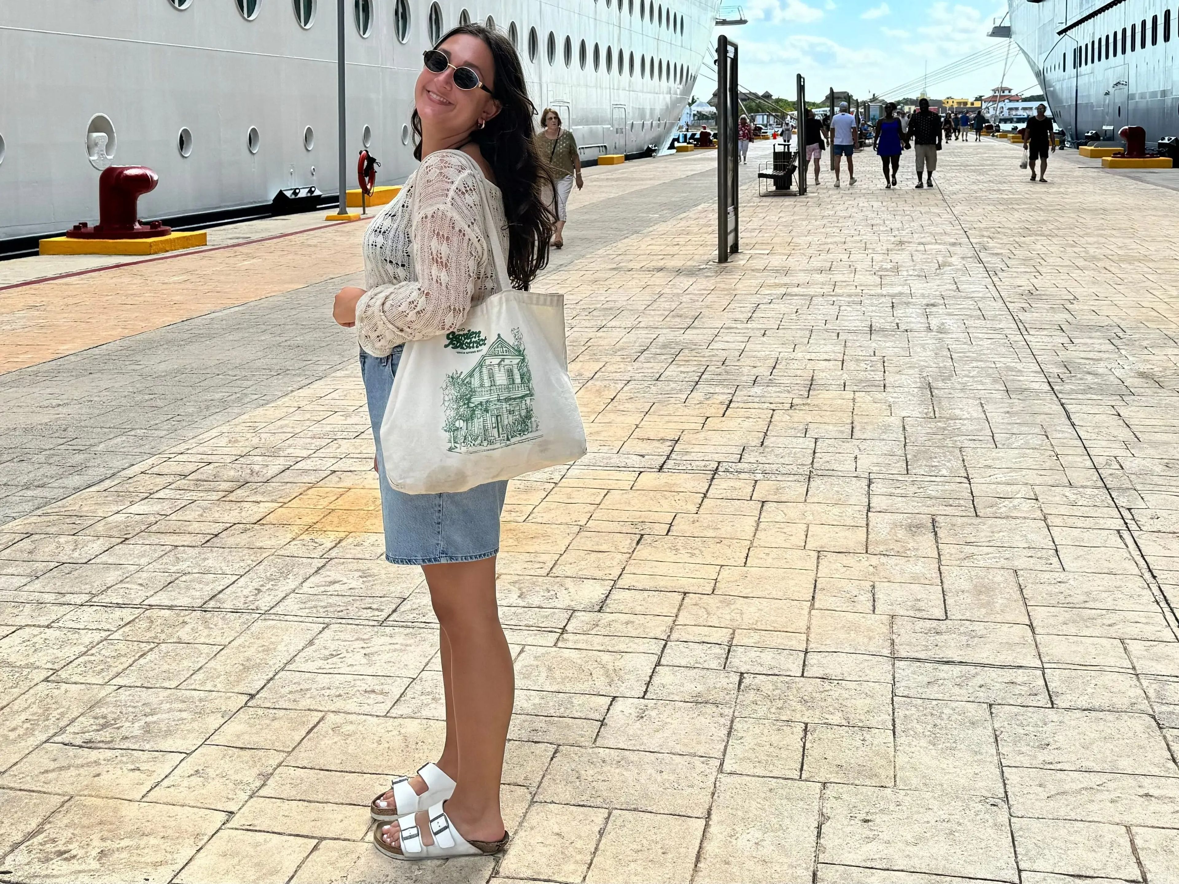 jordana posing in front of a cruise ship carrying a tote bag