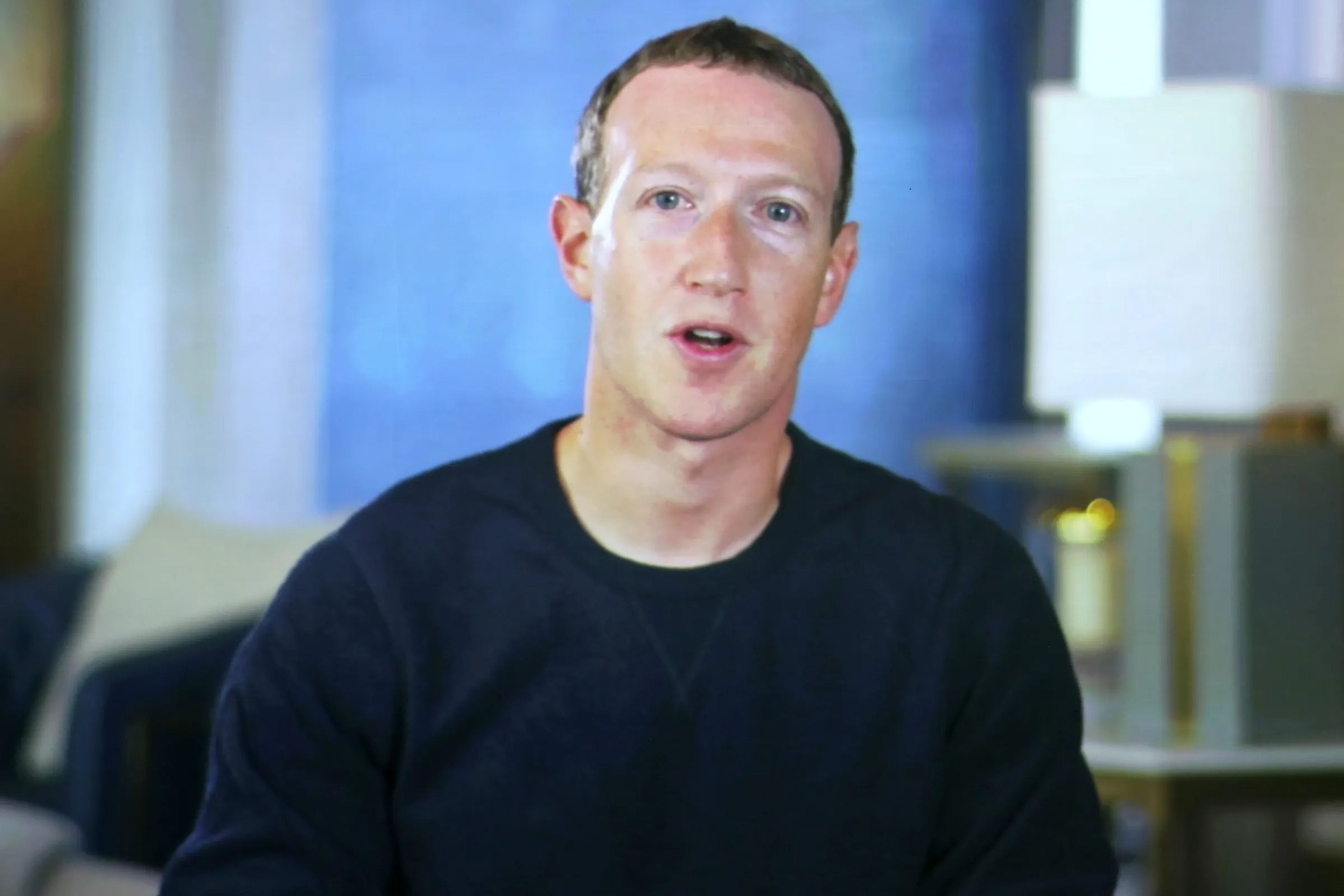 Mark Zuckerberg appearing at a web conference wearing a navy sweatshirt