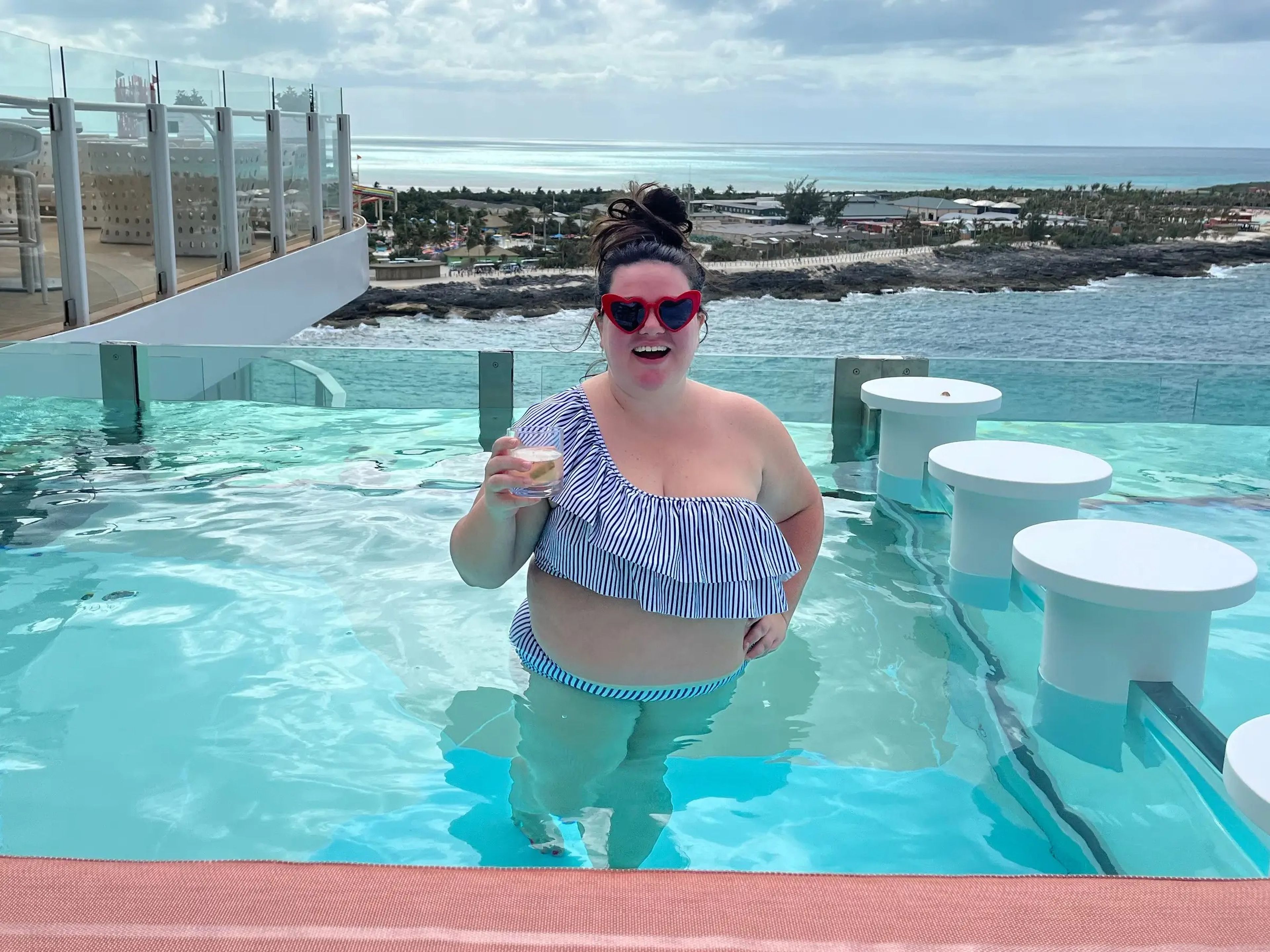 megan in an infinity pool on a cruise ship holding a cocktail