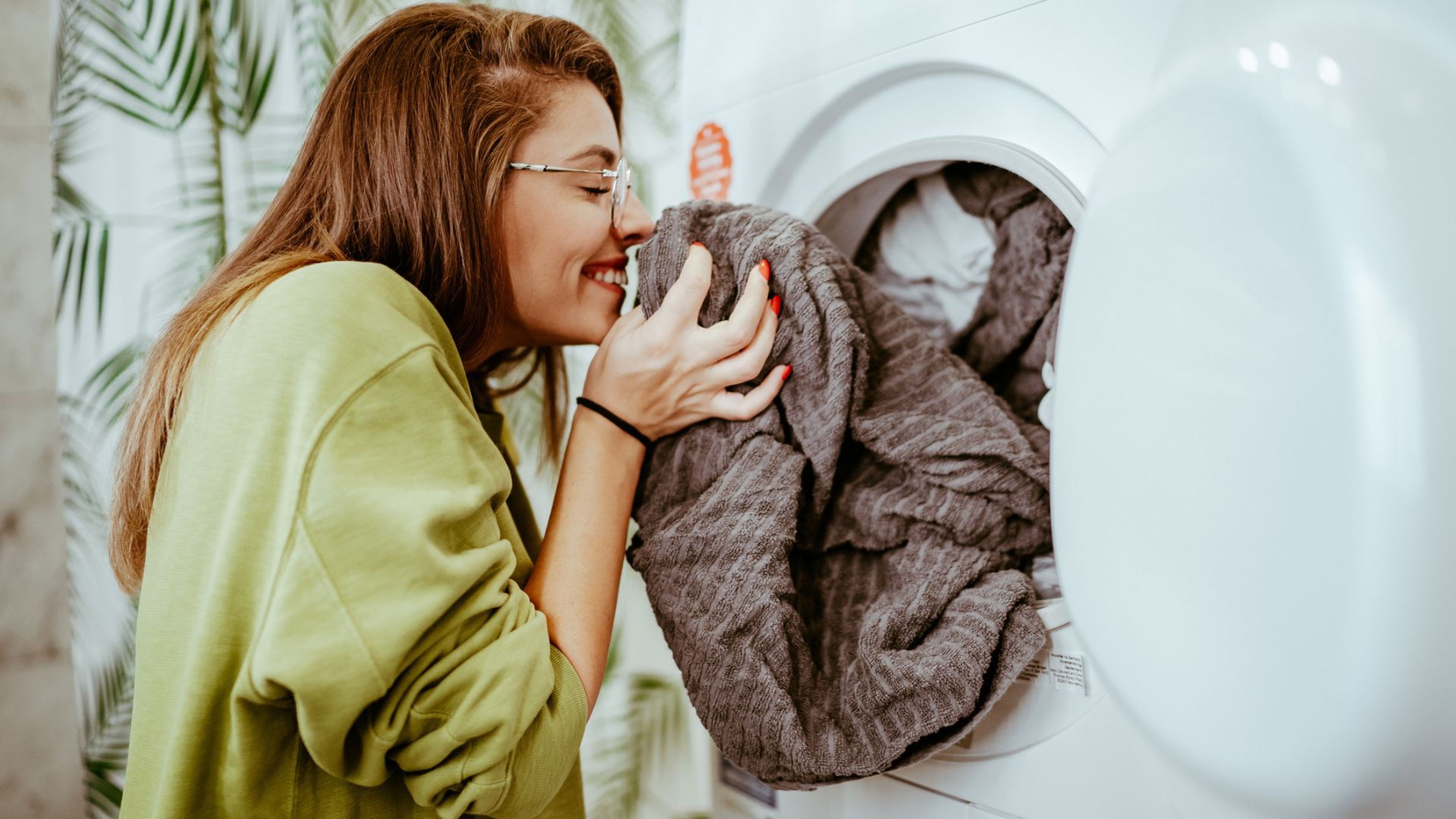 Una mujer huele un albornoz recién sacado de la lavadora.