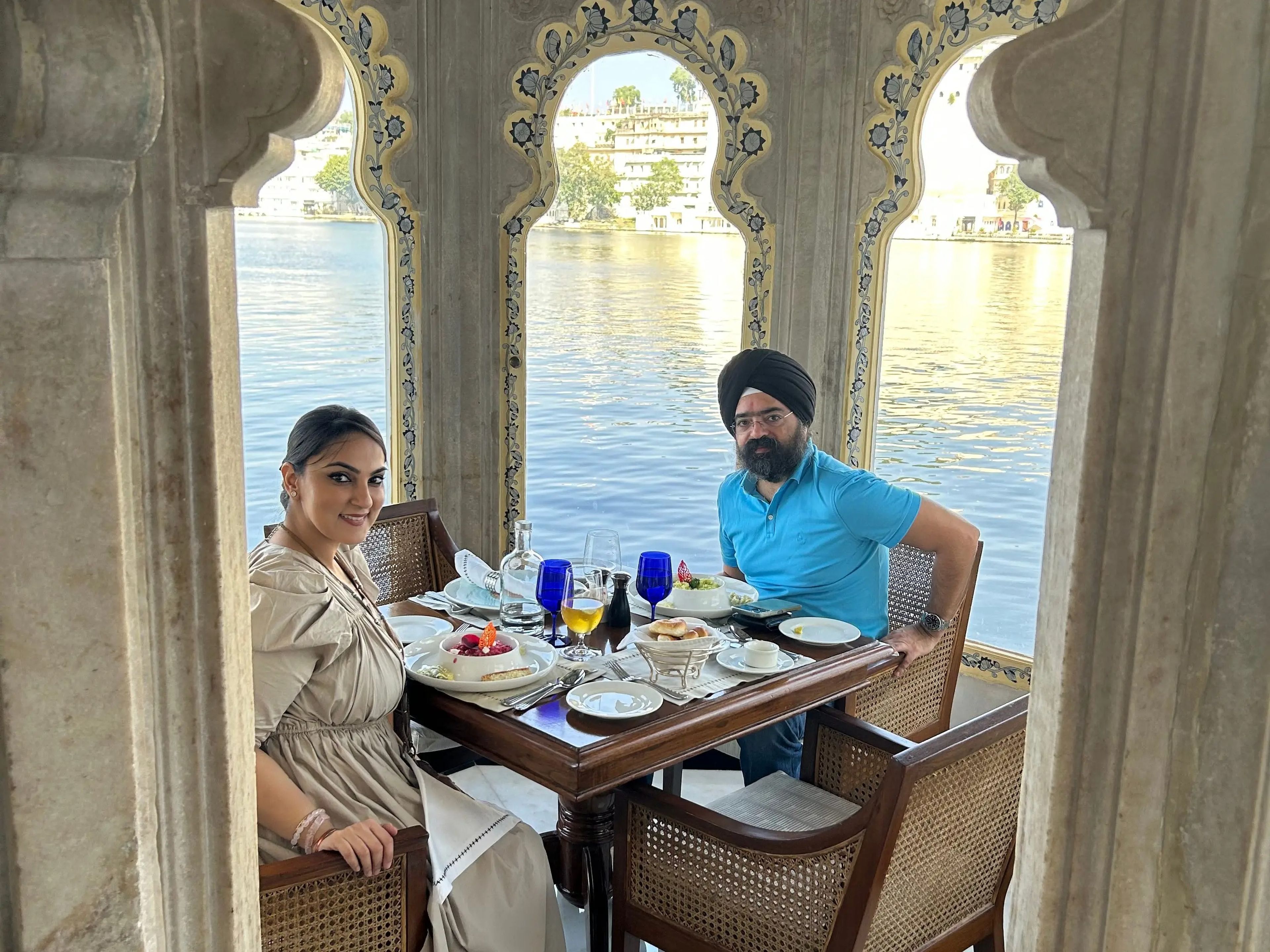 Noor and her husband eating in a private area surrounded by columns next to the lake.