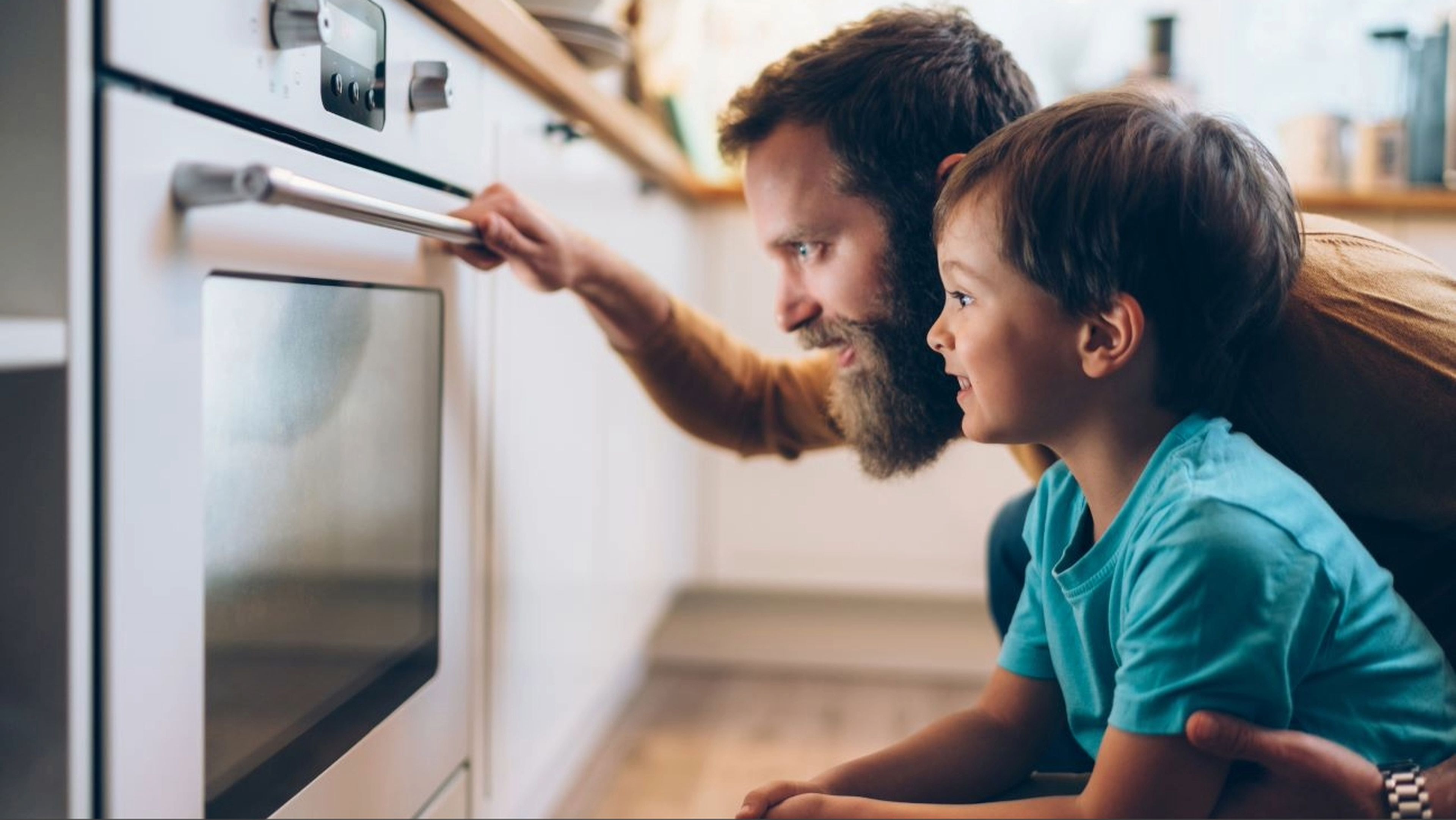 Padre e hijo miran un horno en la cocina
