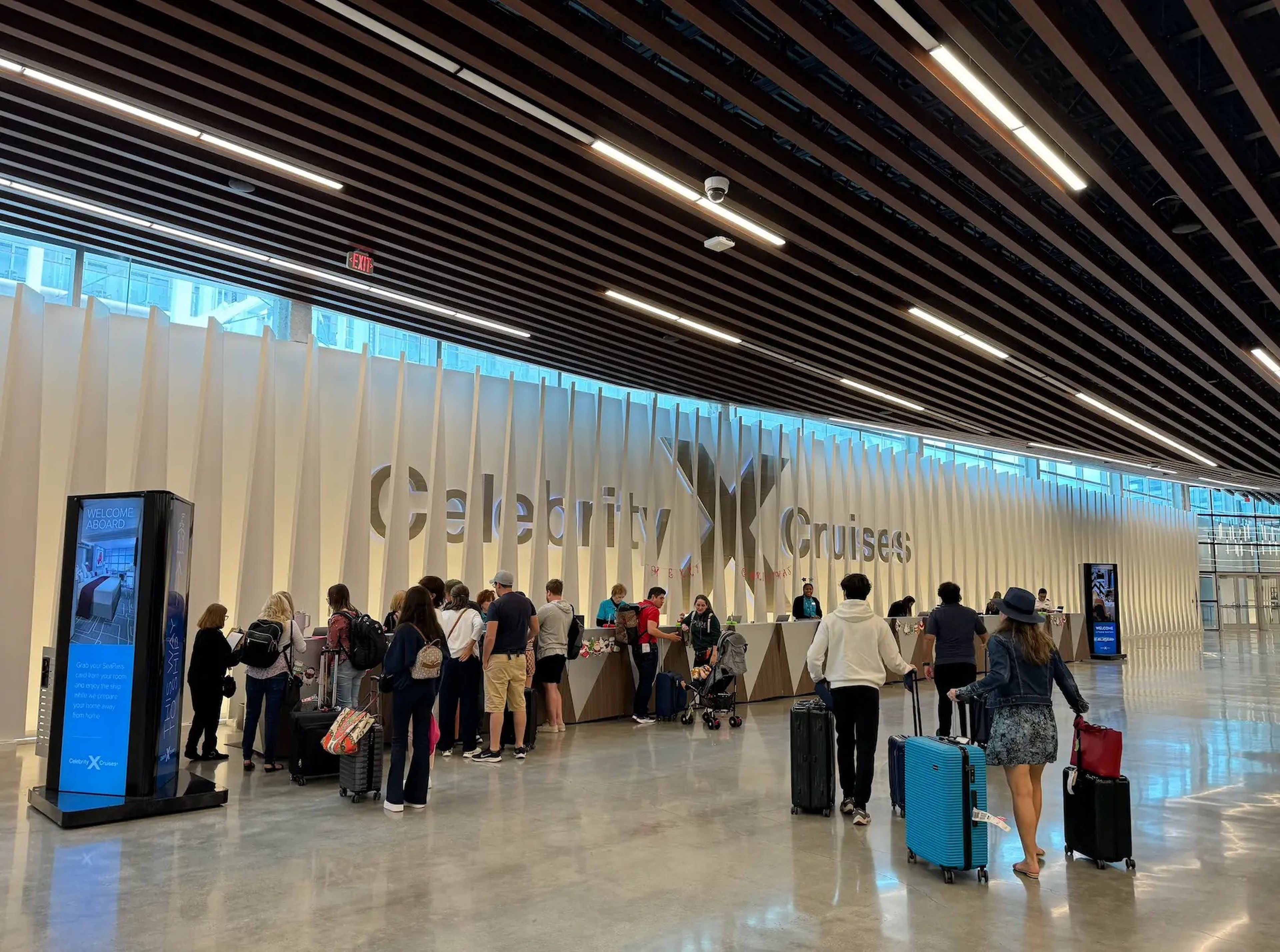 people gathering around a desk at a cruise terminal waiting to check in