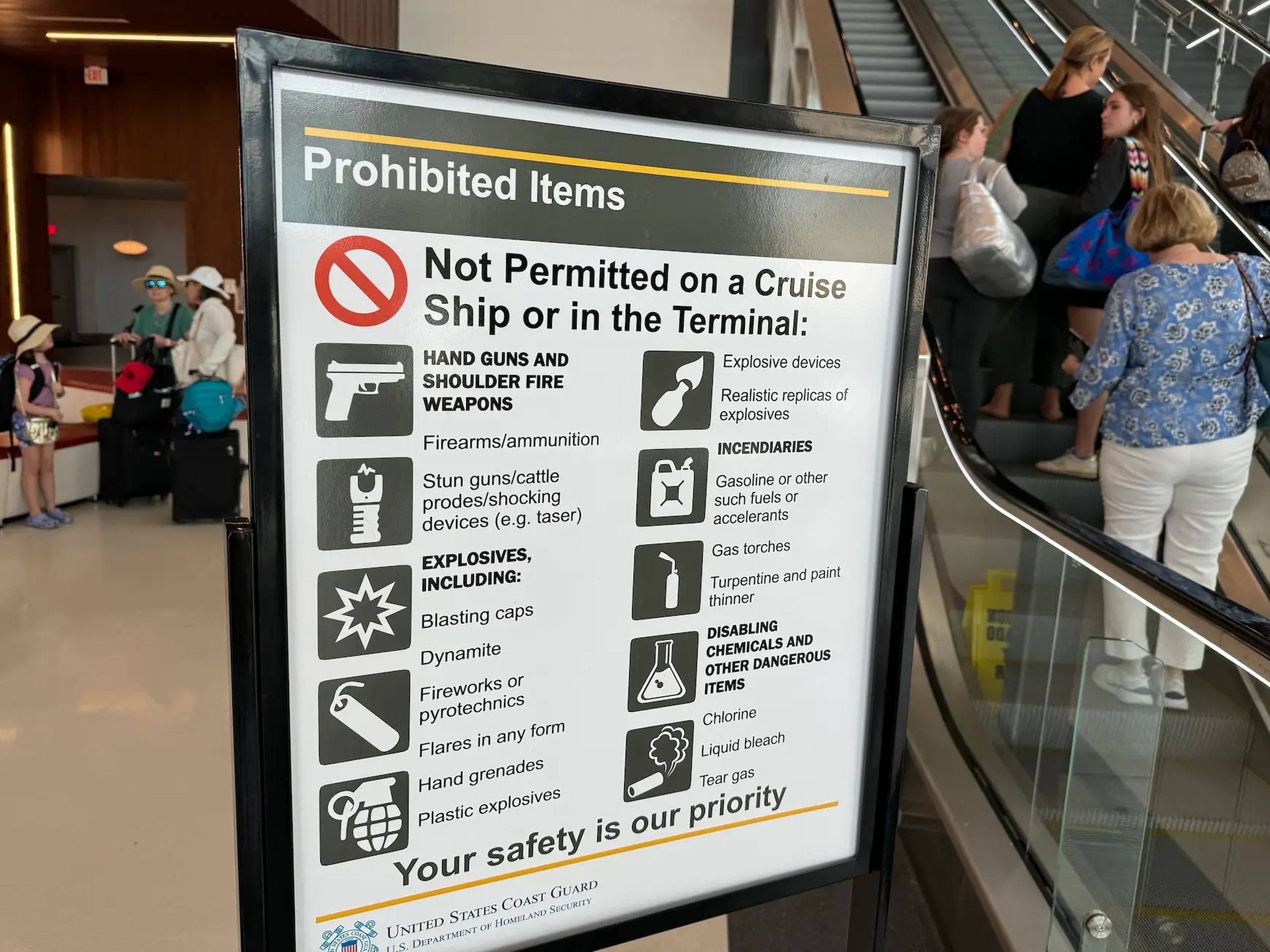 photo of sign listing prohibited items to bring on a cruise ship placed in front of an escalator