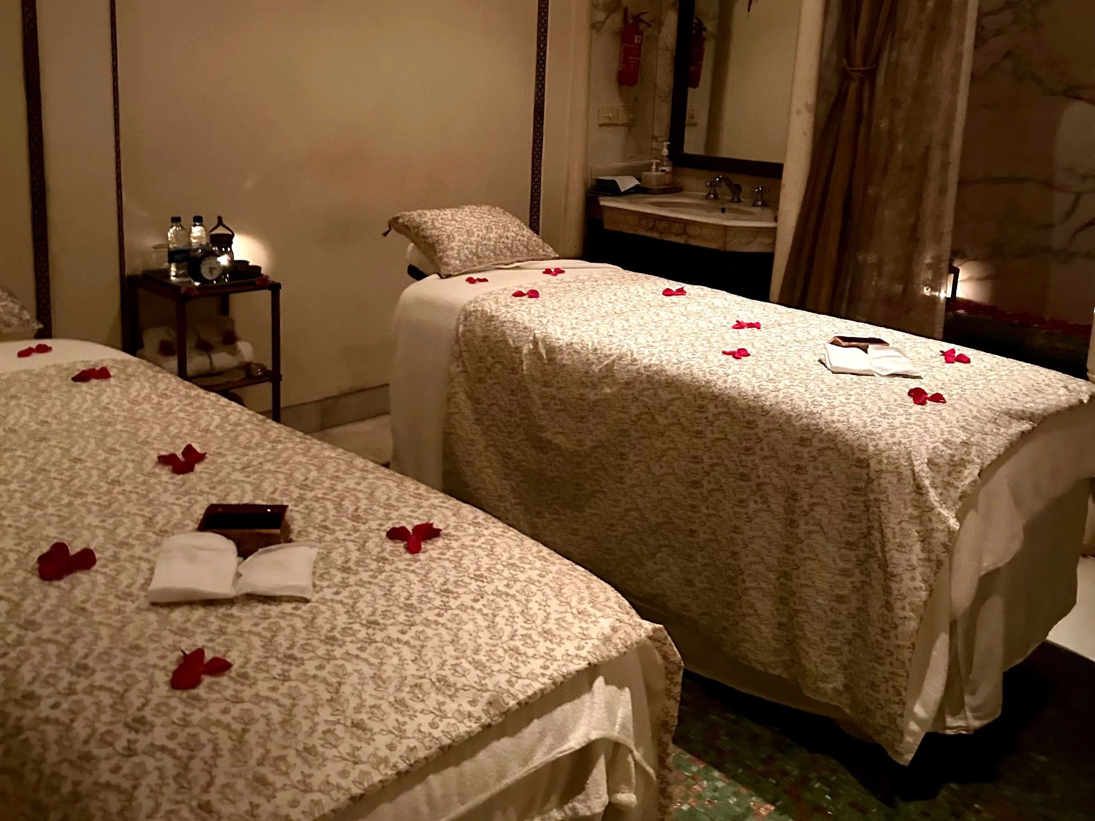 Two massage beds with rose petals on top.