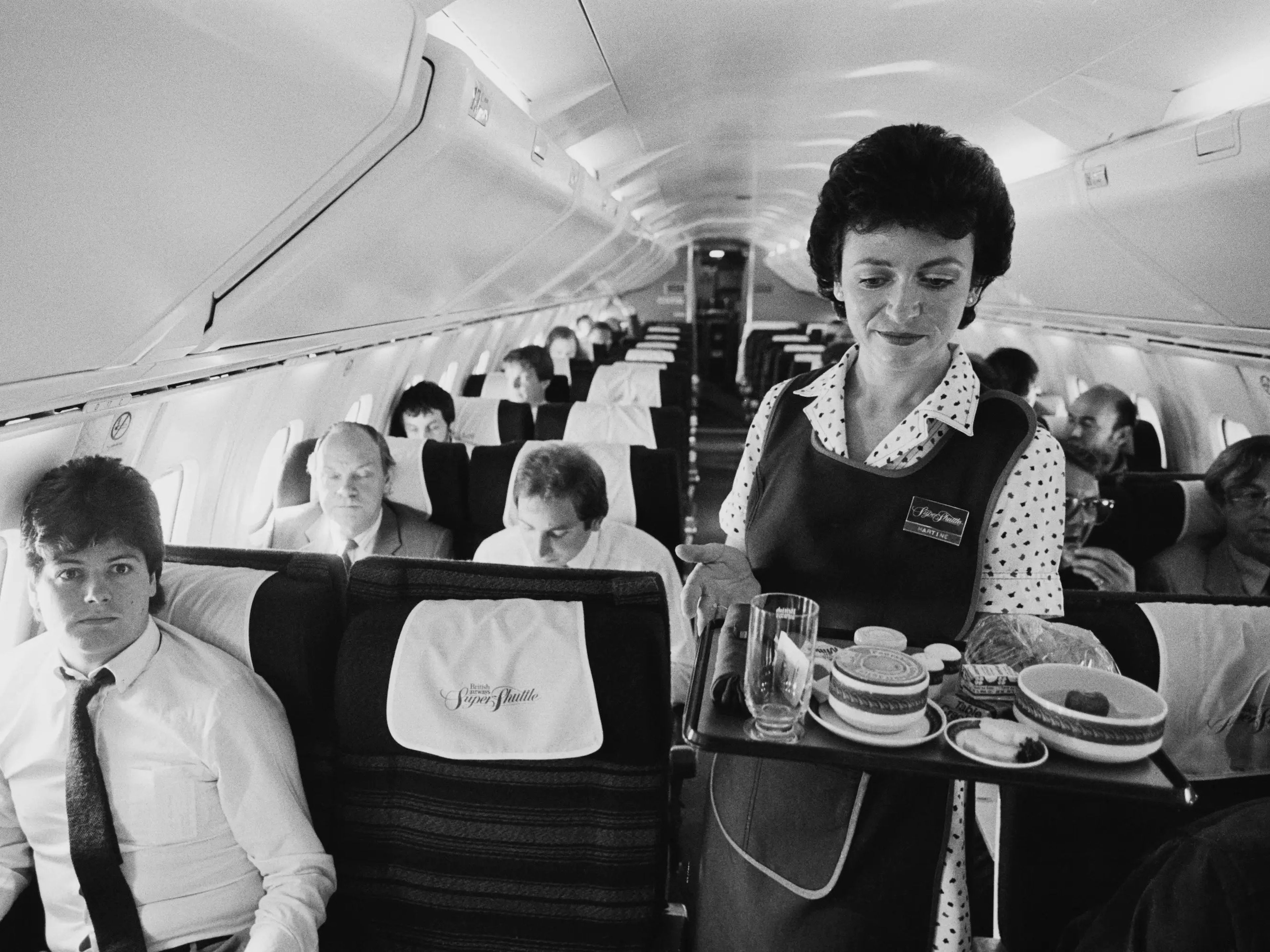 Una azafata sirve comida y bebida en la cabina de primera clase de un Concorde.