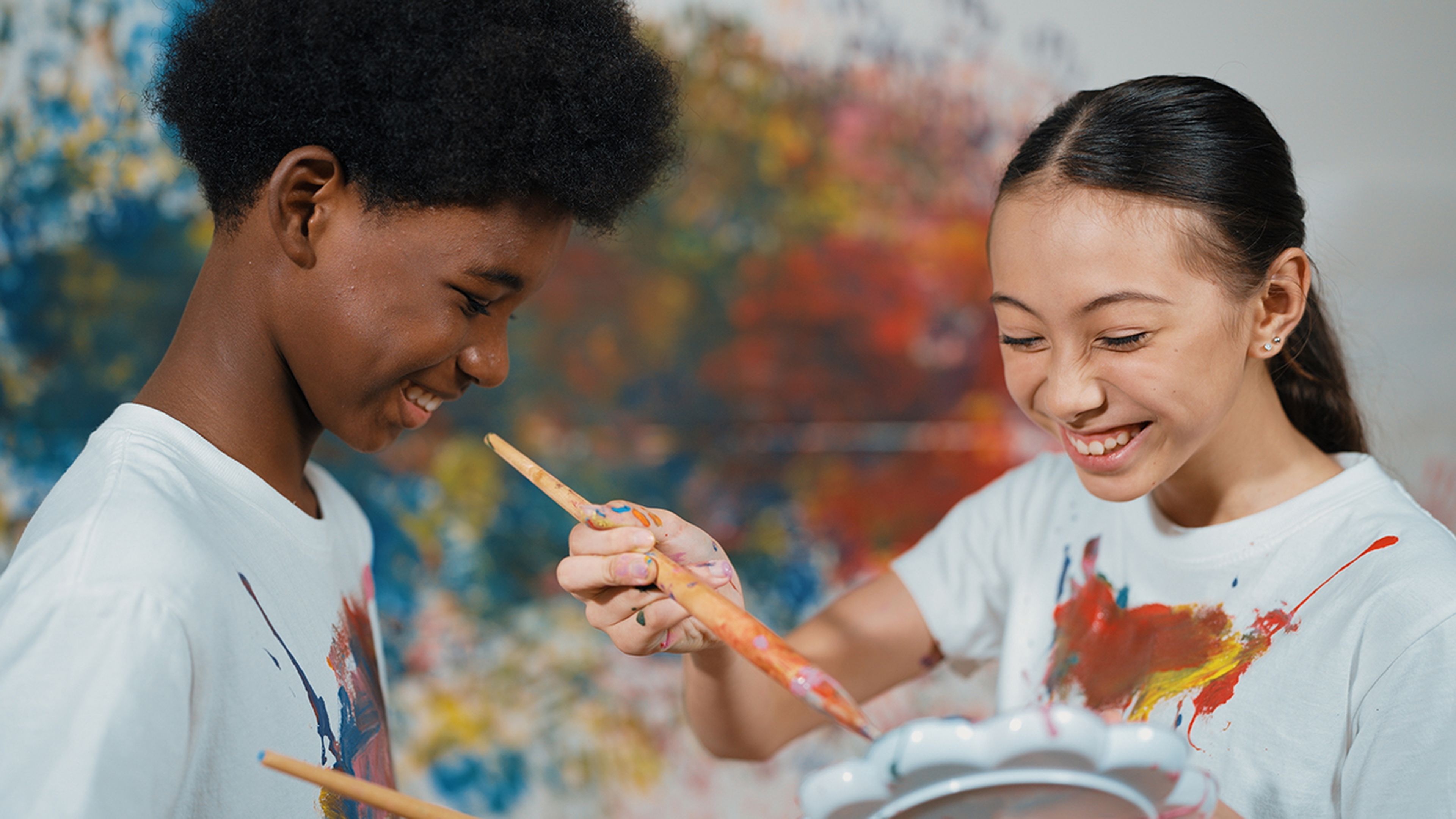 Dos niños pintando con la camiseta sucia