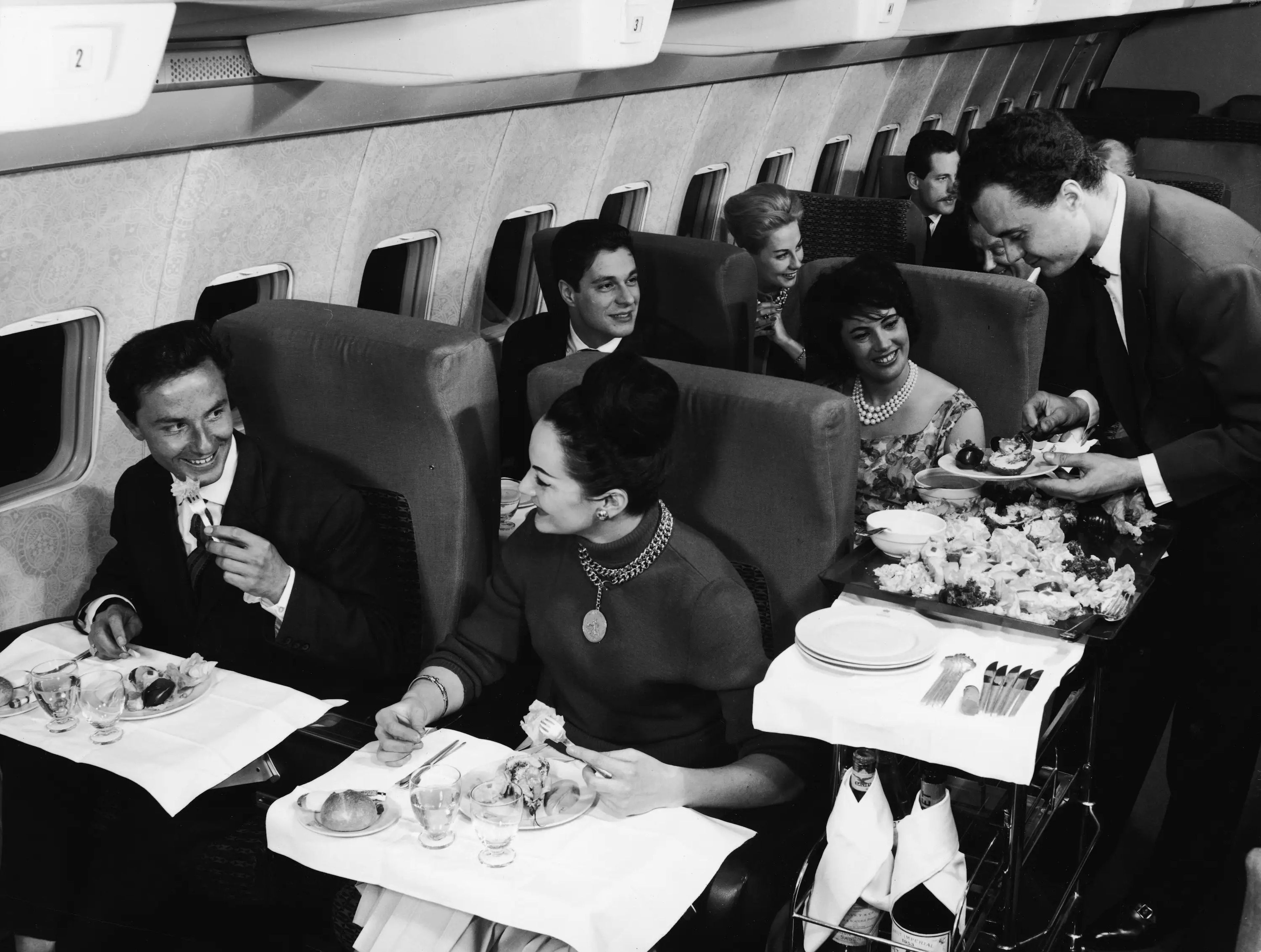 Pasajeros comen en un vuelo en primera clase en los años 50.